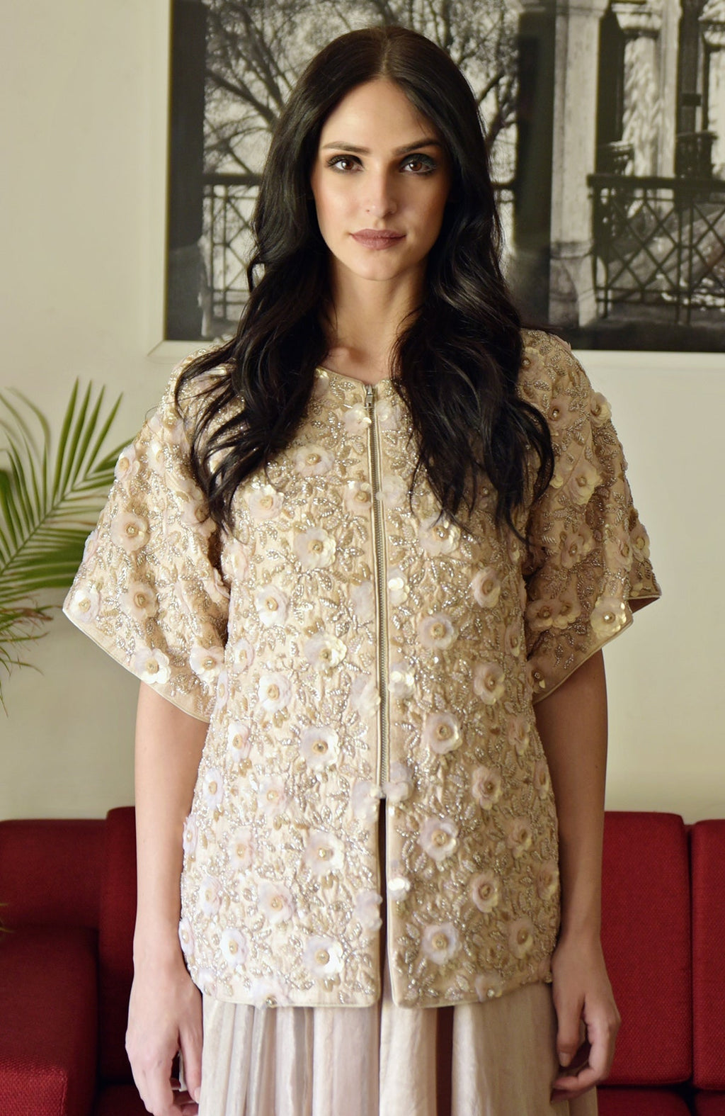 A woman models a light peach sequin and beaded hand-embroidered peplum jacket.