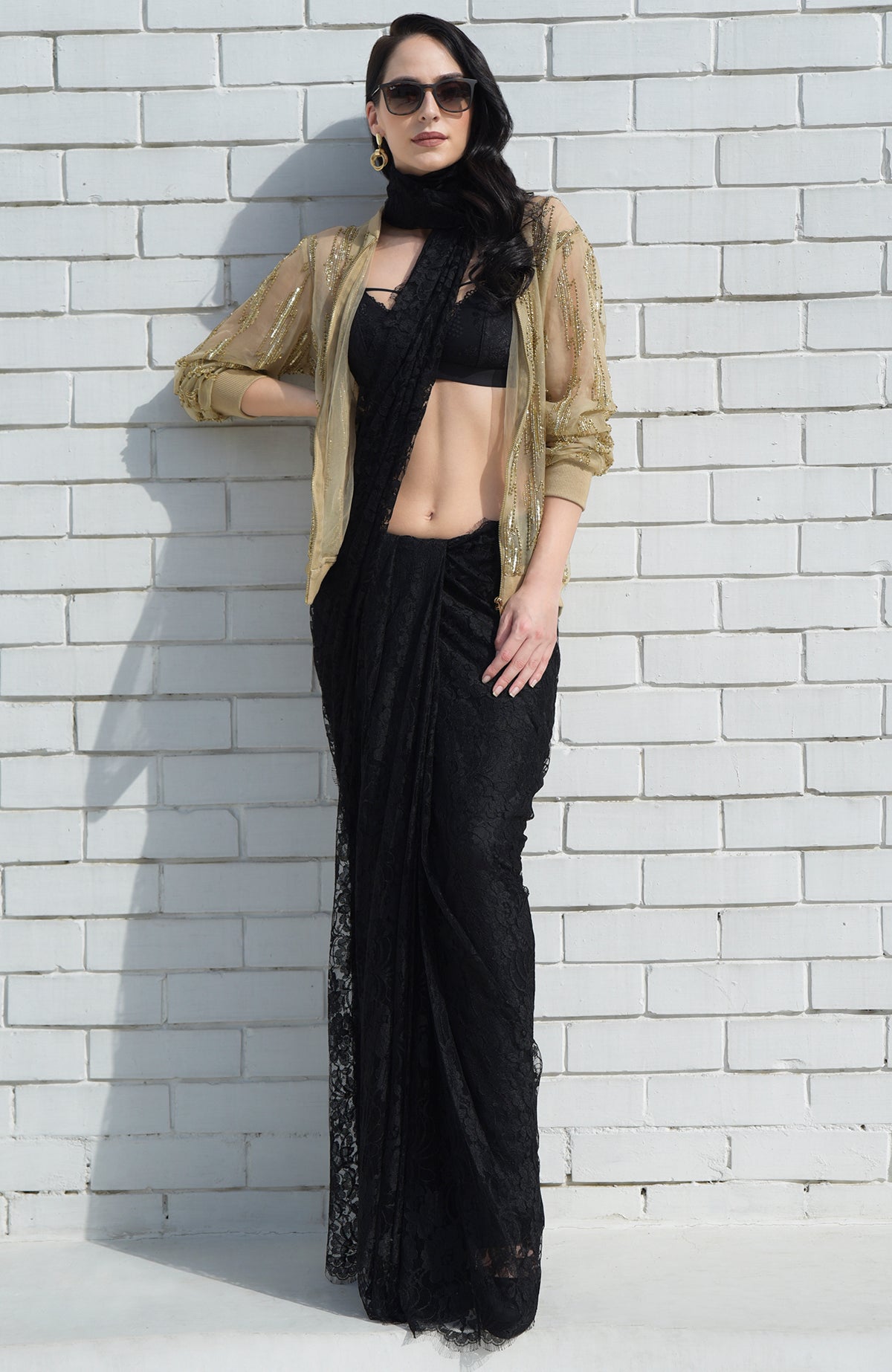 A woman models a gold sequin jacket over a black lace saree.