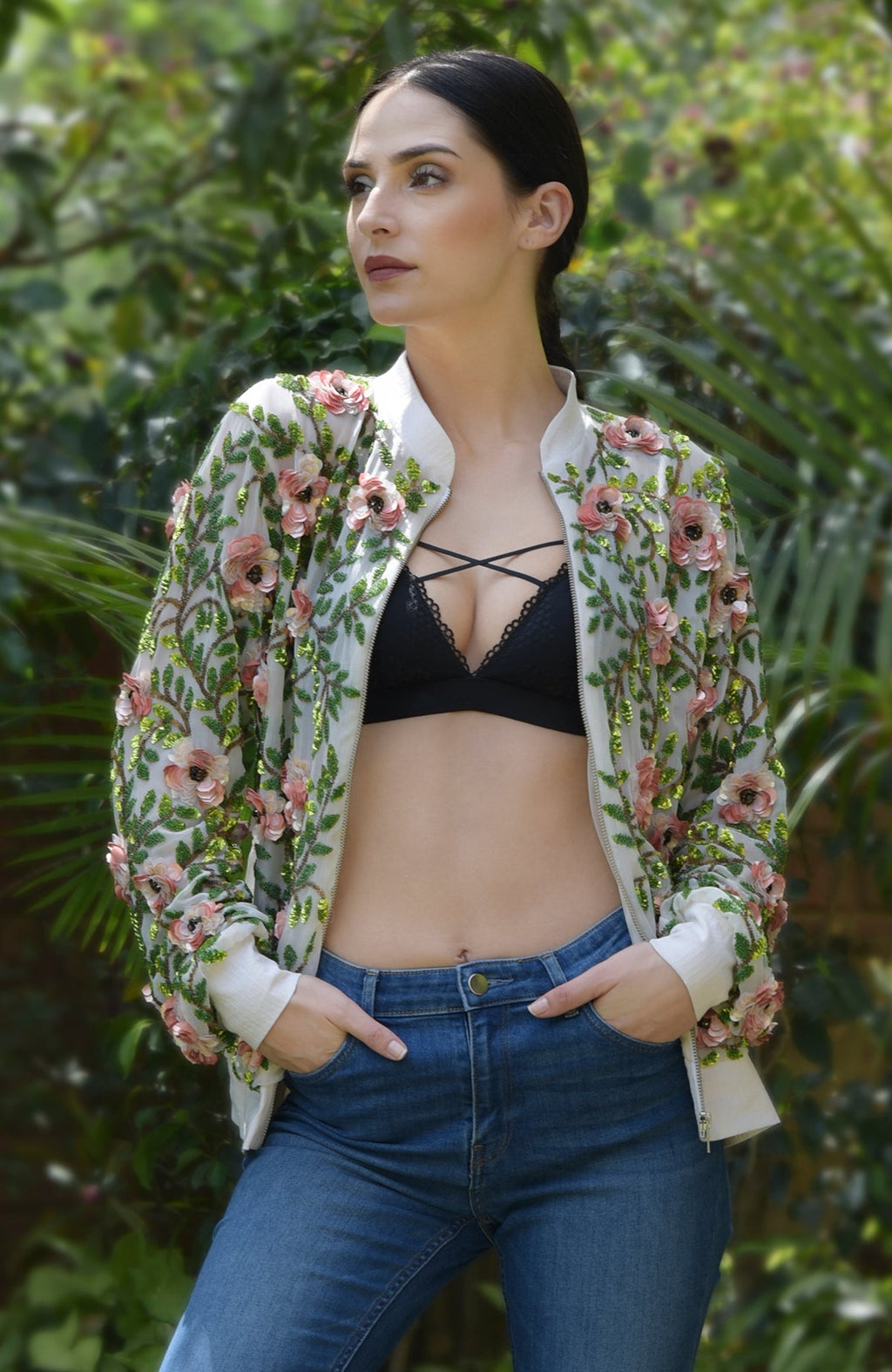 A woman models a cream bomber jacket with 3D floral and beaded leaf embroidery.