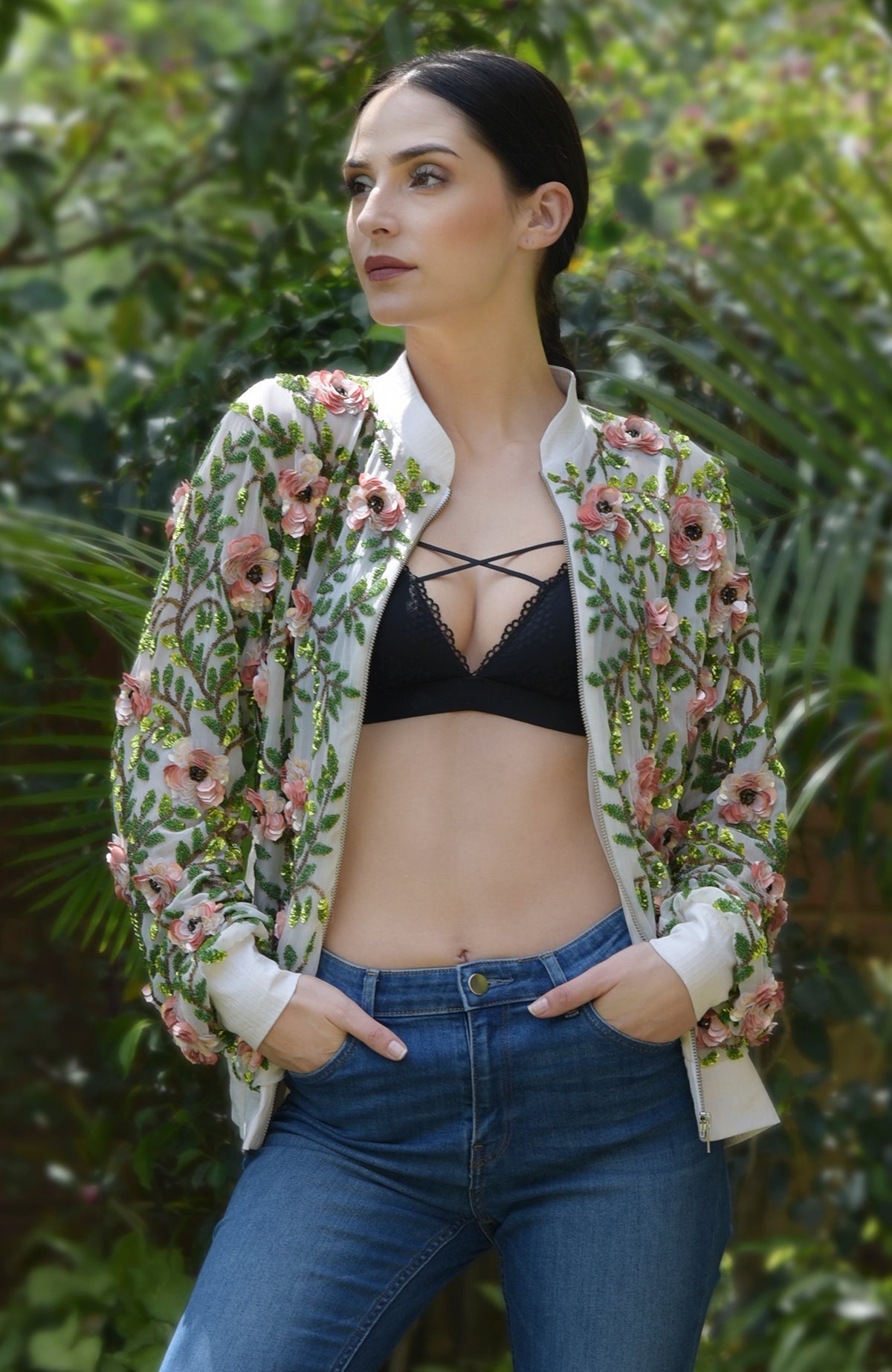 A woman models a cream bomber jacket with 3D floral and beaded leaf embroidery.