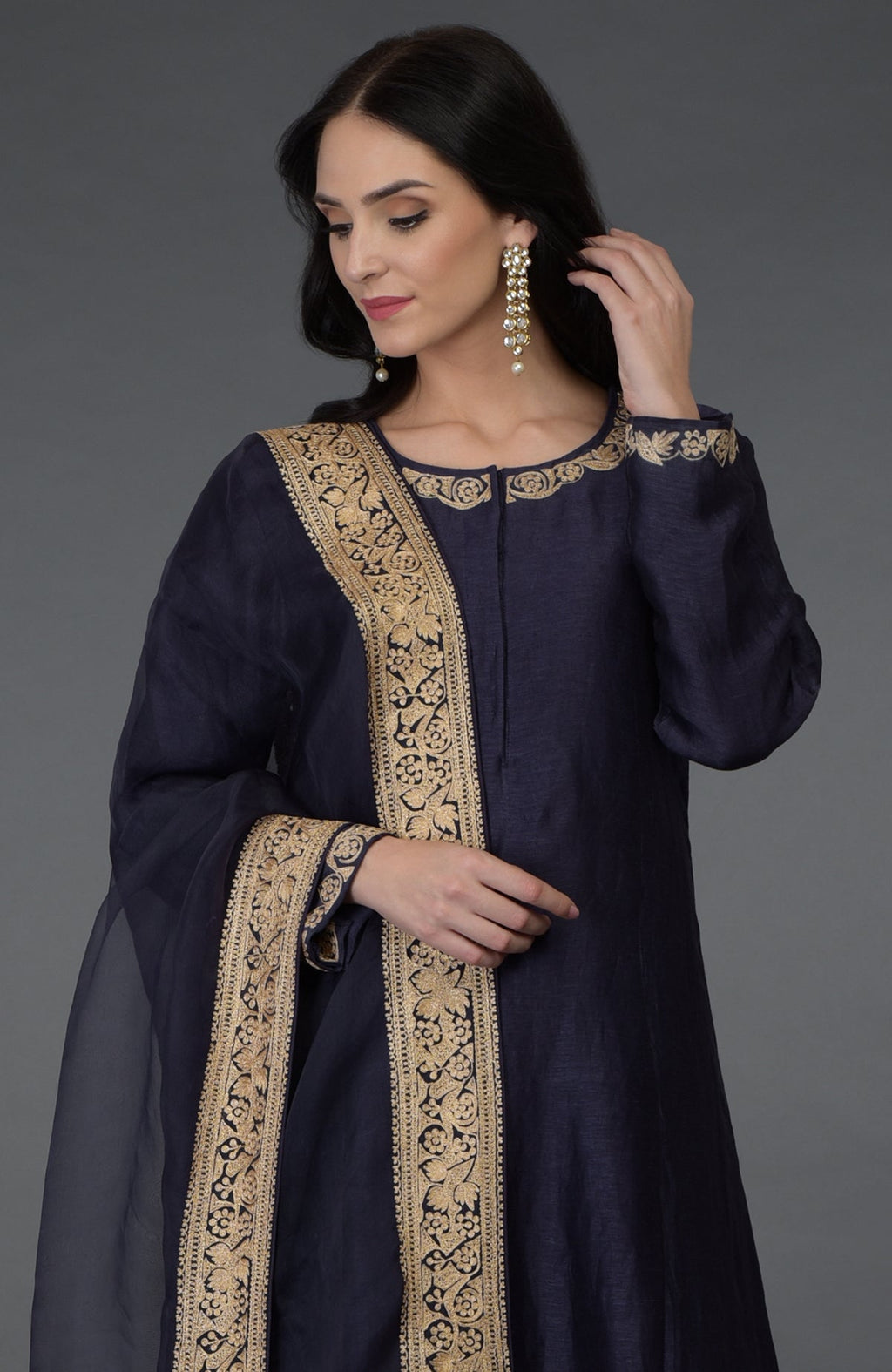A woman models an eclipse blue tilla embroidered suit with gold embroidery.