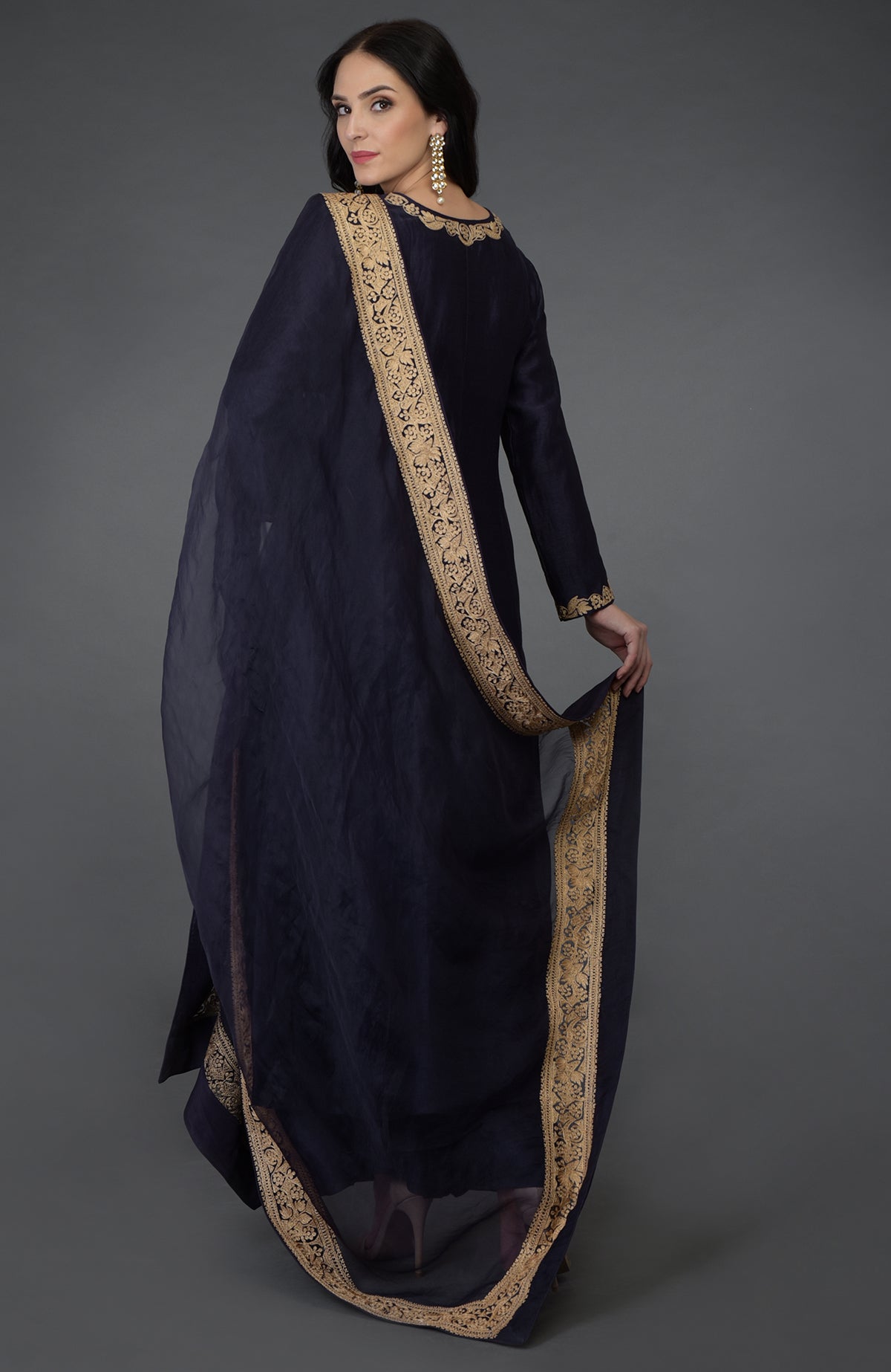 A woman in an eclipse blue tilla embroidered suit with a gold border on the dupatta.