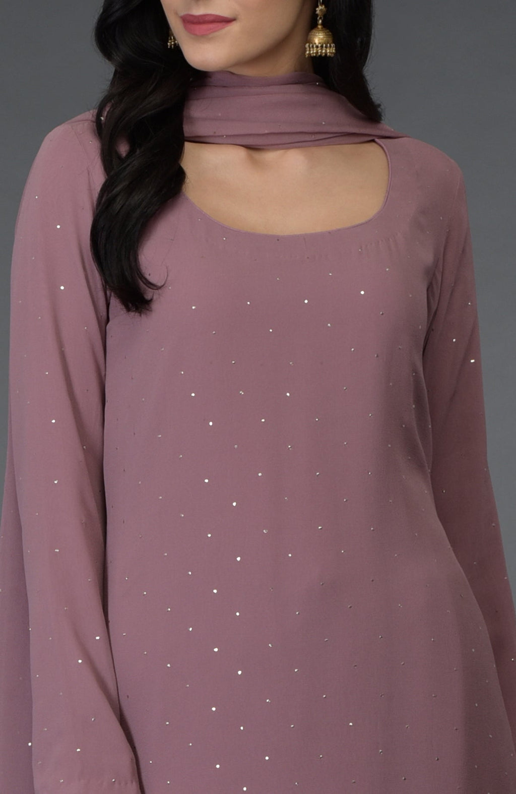 A woman wears a lilac suit with scattered gold mukaish embroidery and a scoop neckline.