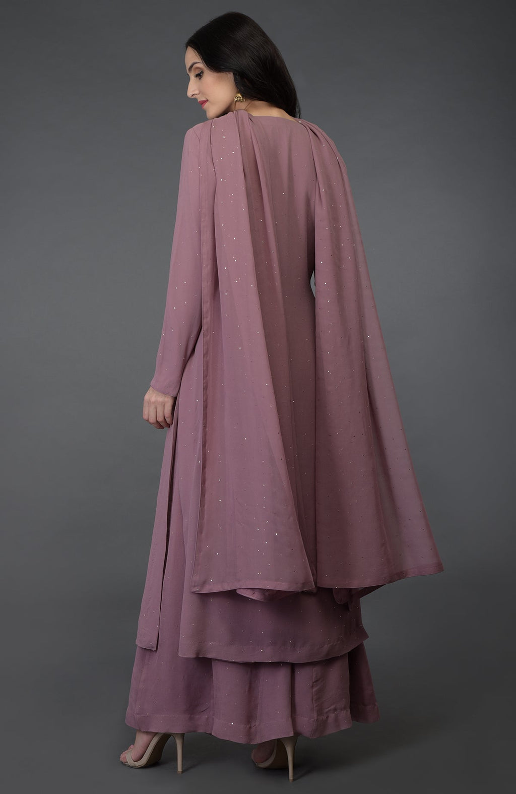 A woman models a lilac handcrafted mukaish farshi palazzo suit with a flowing cape.