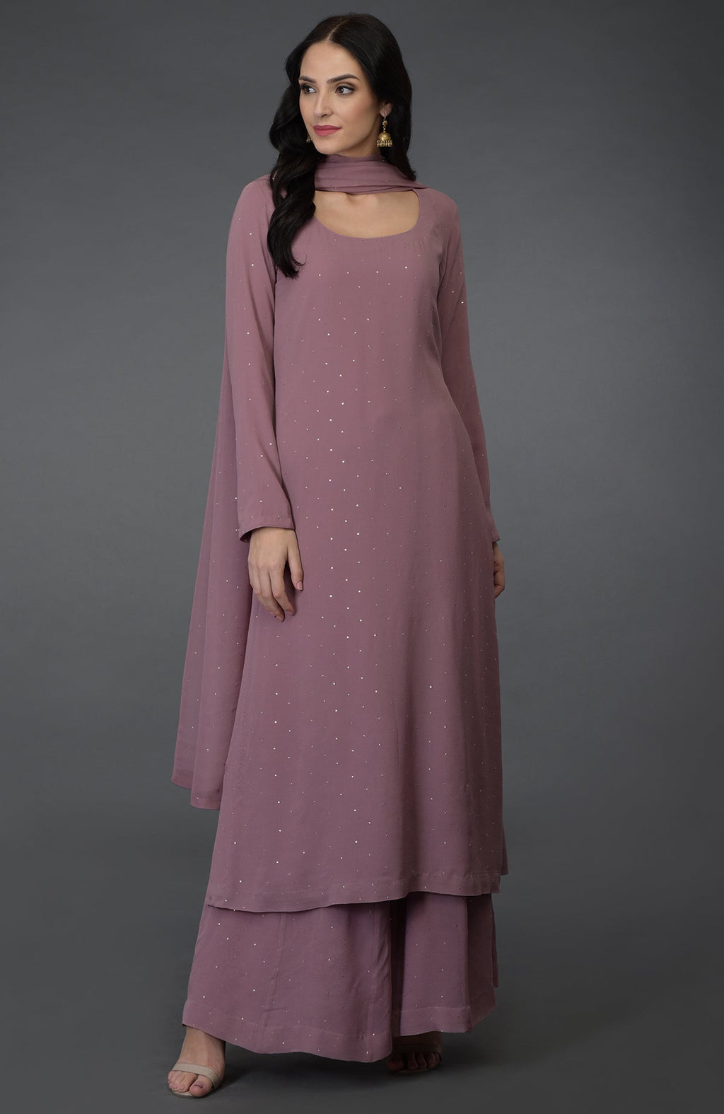 A woman models a lilac handcrafted mukaish farshi palazzo suit with a scoop neckline.