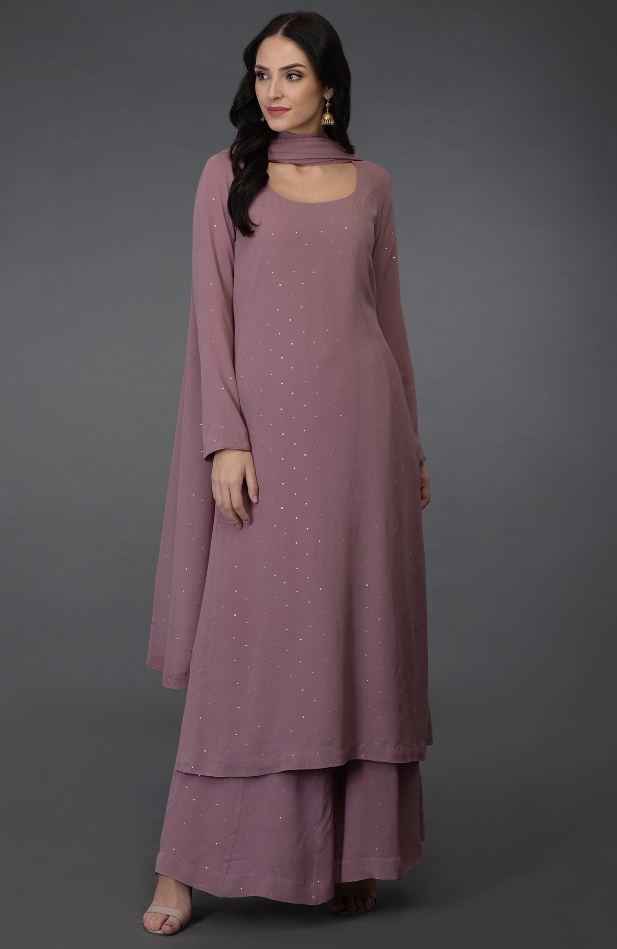 A woman models a lilac handcrafted mukaish farshi palazzo suit with a scoop neckline.