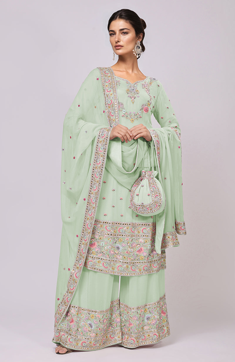 A woman models a light green sharara set with intricate embroidery and a matching potli bag.
