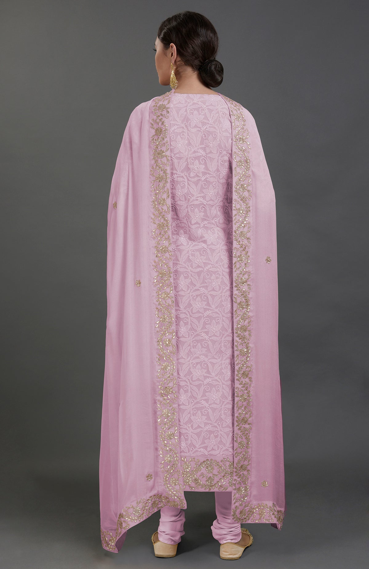 A woman from behind wears a lilac chikankari kurta set with gold gota patti embroidery.