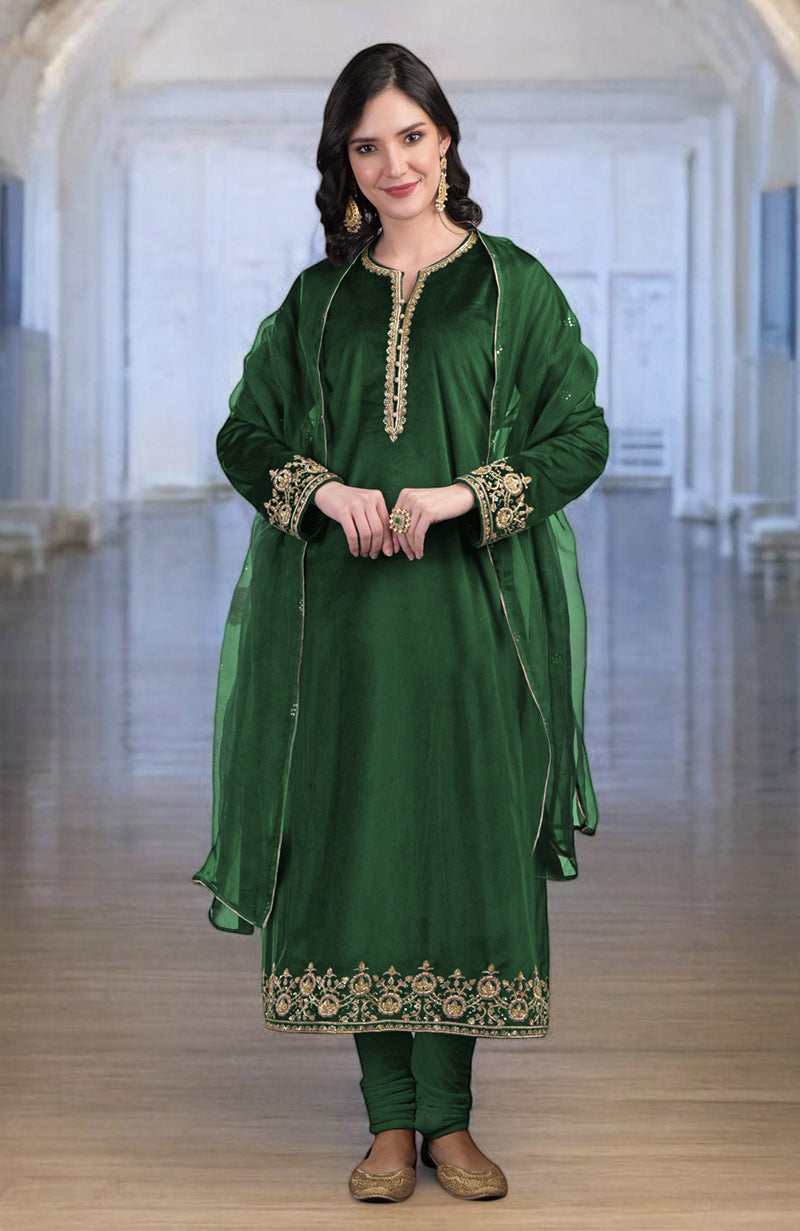 A woman in a green velvet kurta set with gold zardozi embroidery.