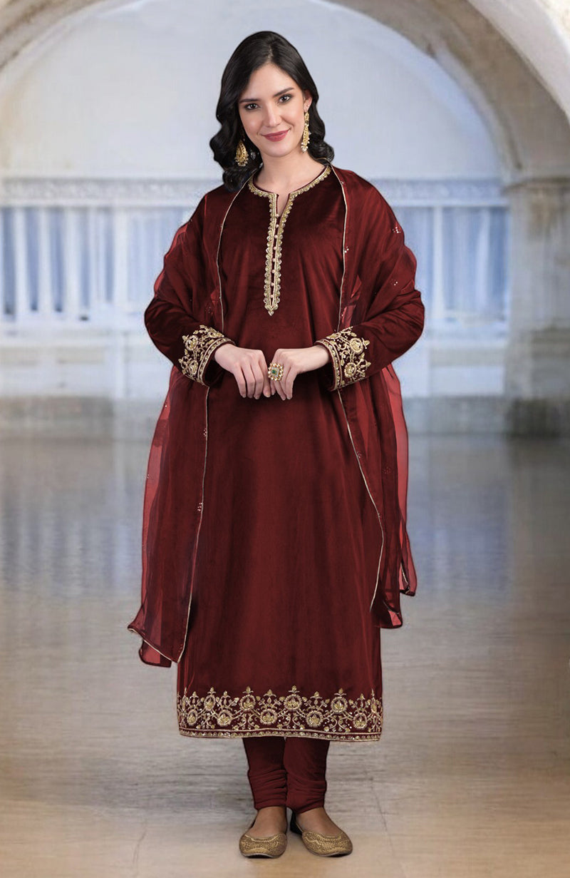 A woman in a maroon velvet kurta set with gold zardozi embroidery and an organza dupatta.