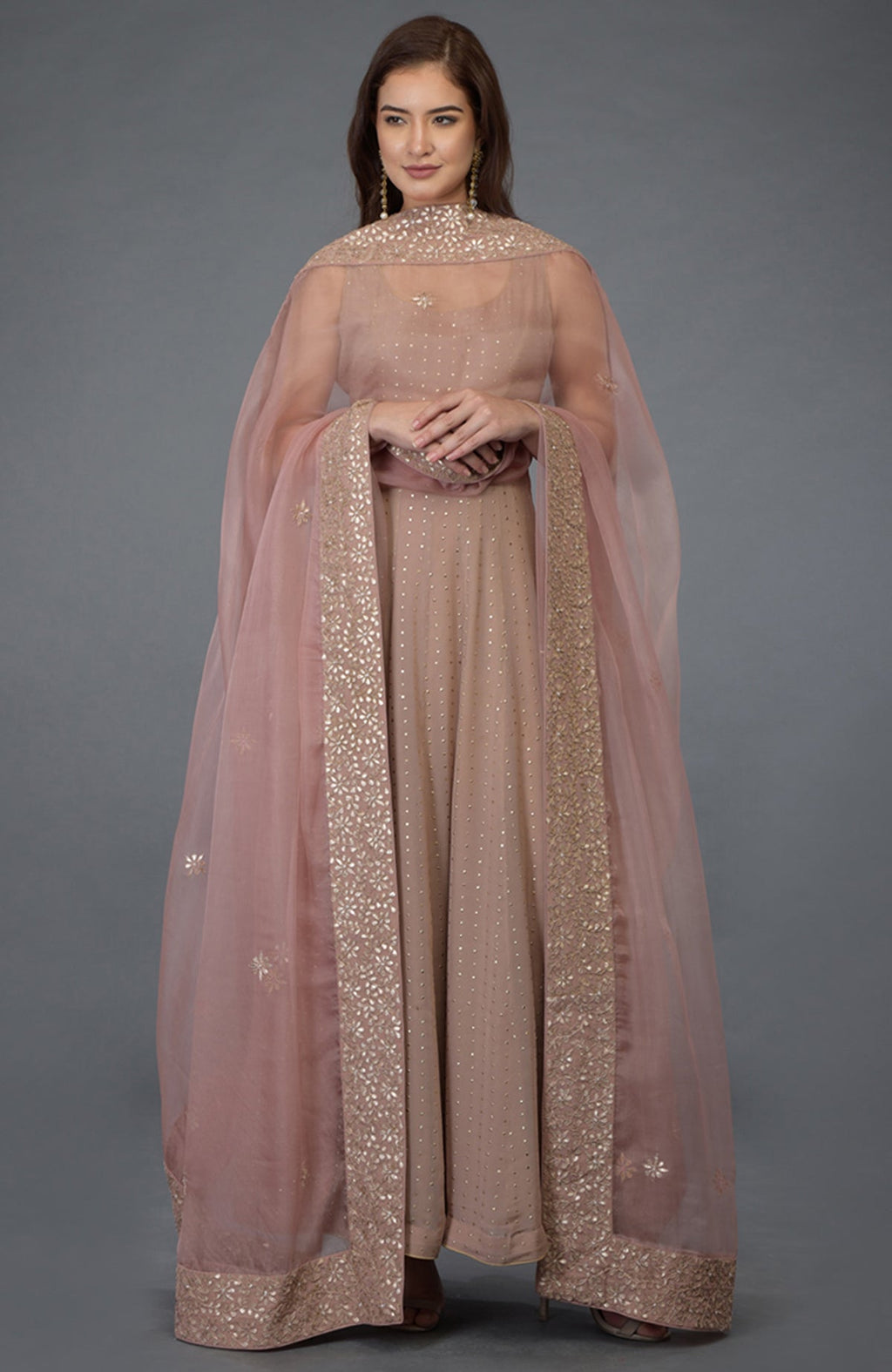 A woman models a dusky pink Anarkali suit with a matching embroidered dupatta.