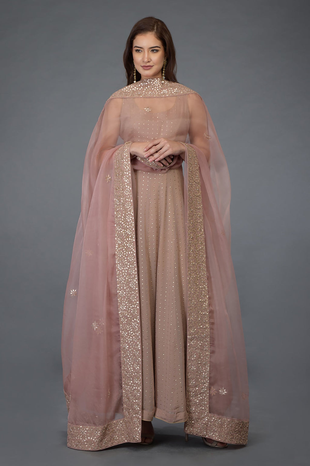 A woman models a dusky pink Anarkali suit with a matching embroidered dupatta.