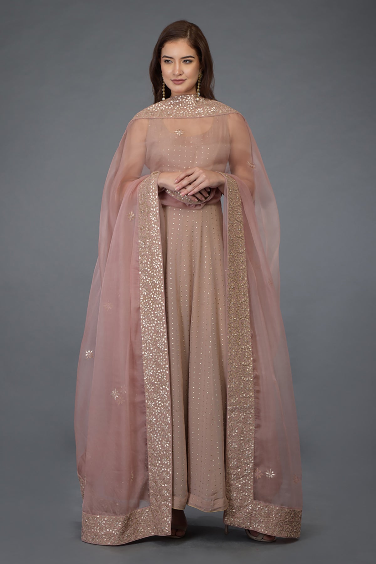 A woman models a dusky pink Anarkali suit with a matching embroidered dupatta.