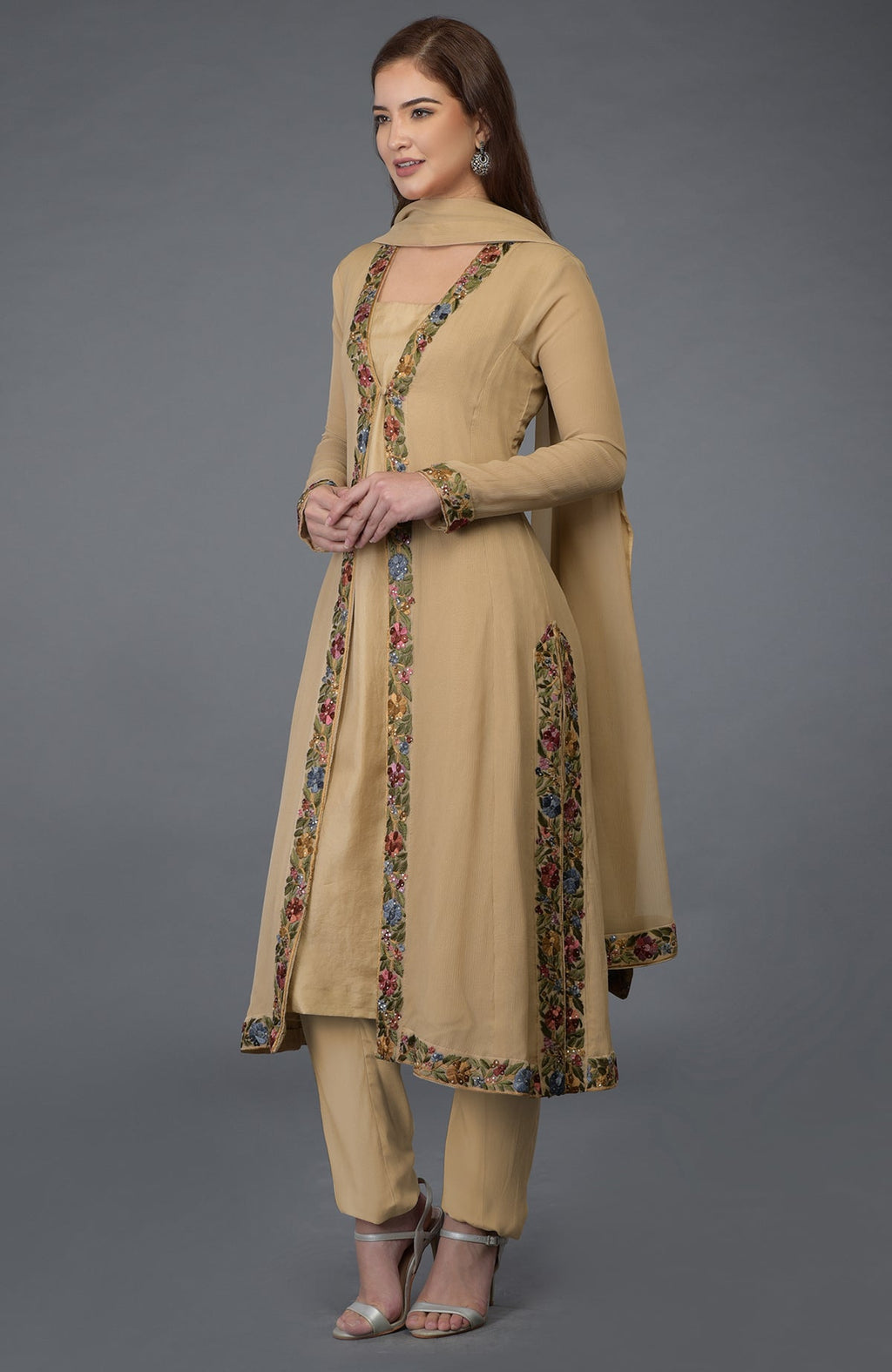 A woman models a beige Parsi Gara embroidered overlay suit with floral details.