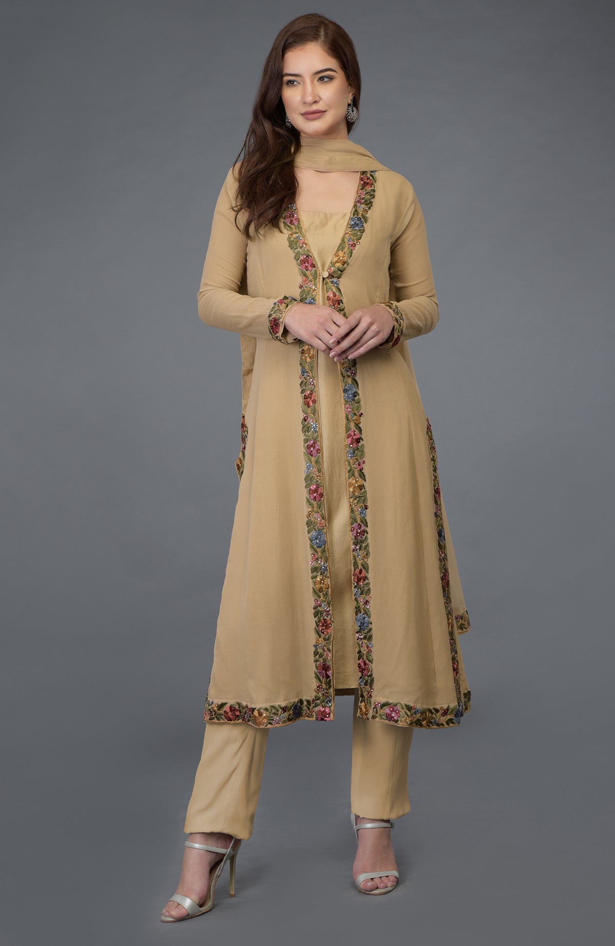 A woman models a beige Parsi Gara embroidered overlay suit with floral details.