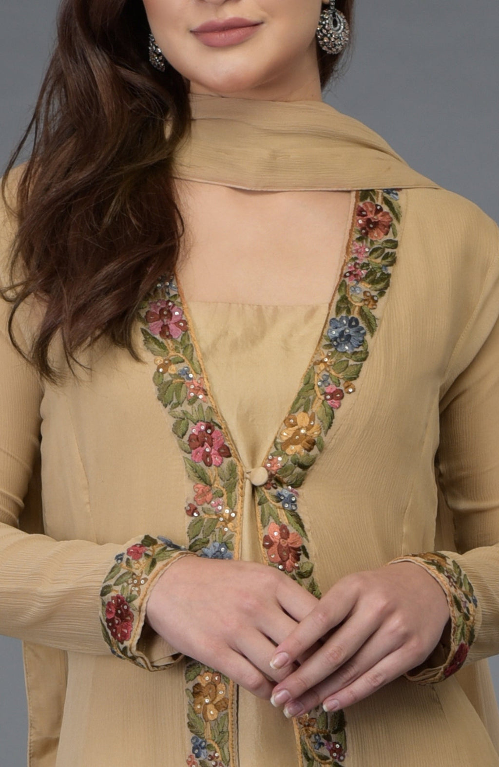 A woman models a beige Parsi Gara embroidered overlay suit with floral details.