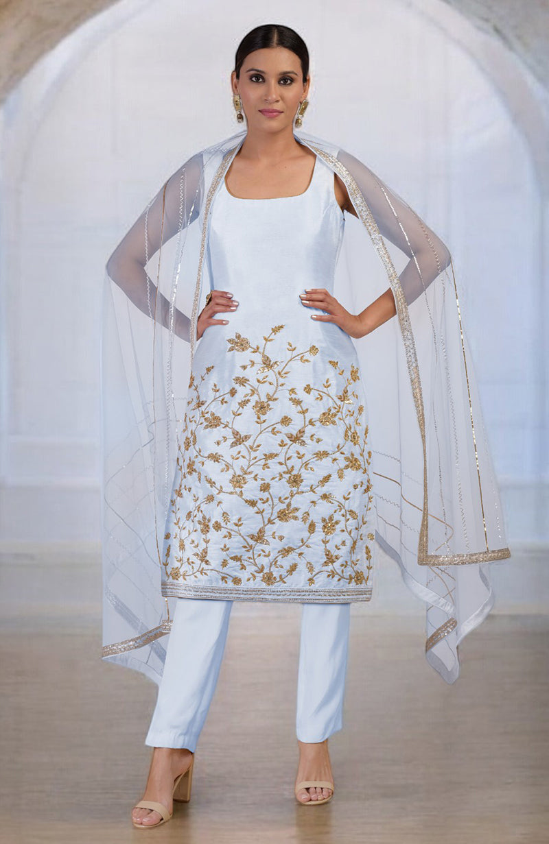 A woman models a light blue kurta set with gold embroidery and a sheer dupatta.