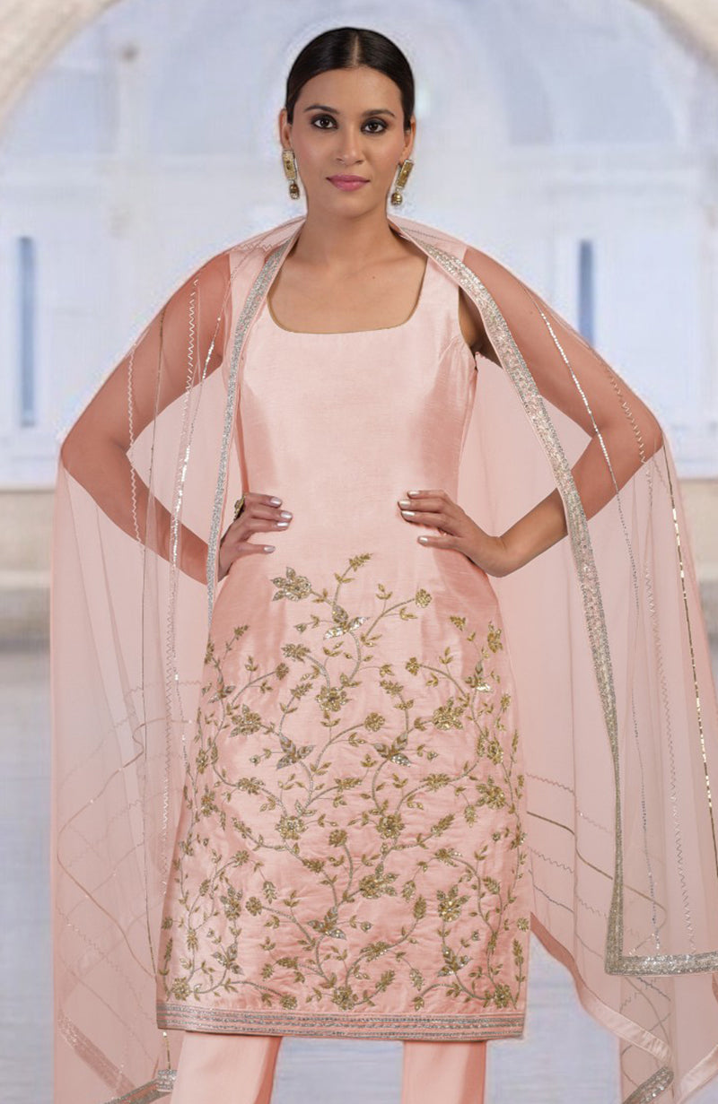 A woman models a rose gold hand-embroidered kurta set with a sheer dupatta.