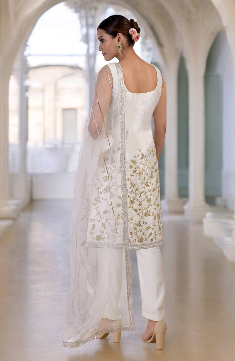 A woman models a white and gold hand-embroidered kurta set with a sheer dupatta.