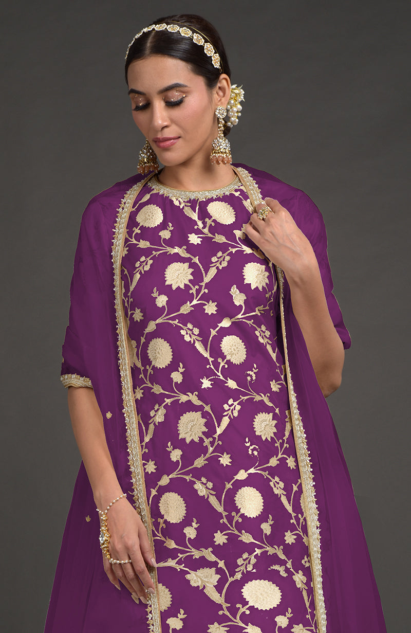 A woman in a purple kurta with gold floral embroidery and a matching dupatta.
