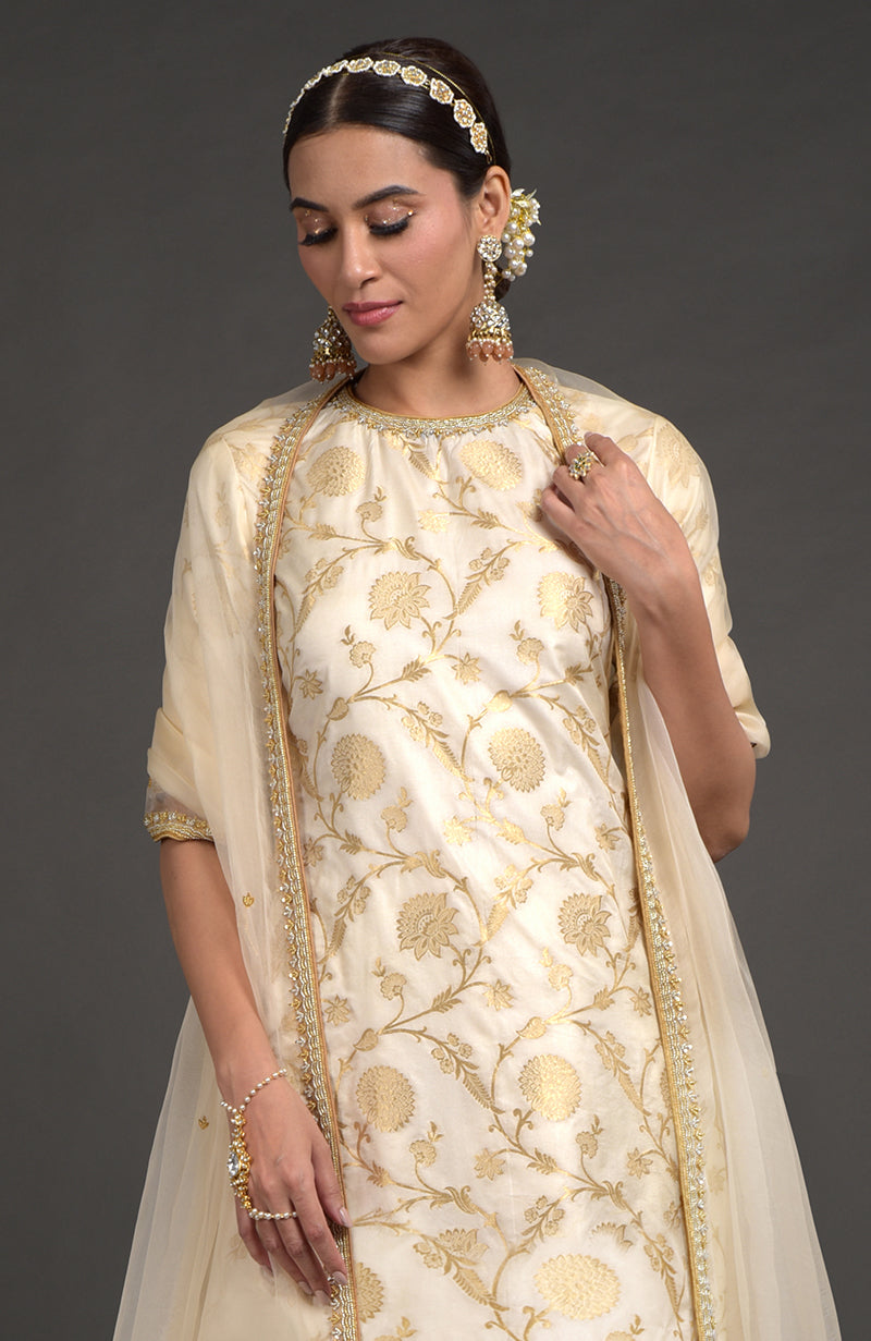 An Indian woman models an ivory Benarasi weave zardozi kurta set.