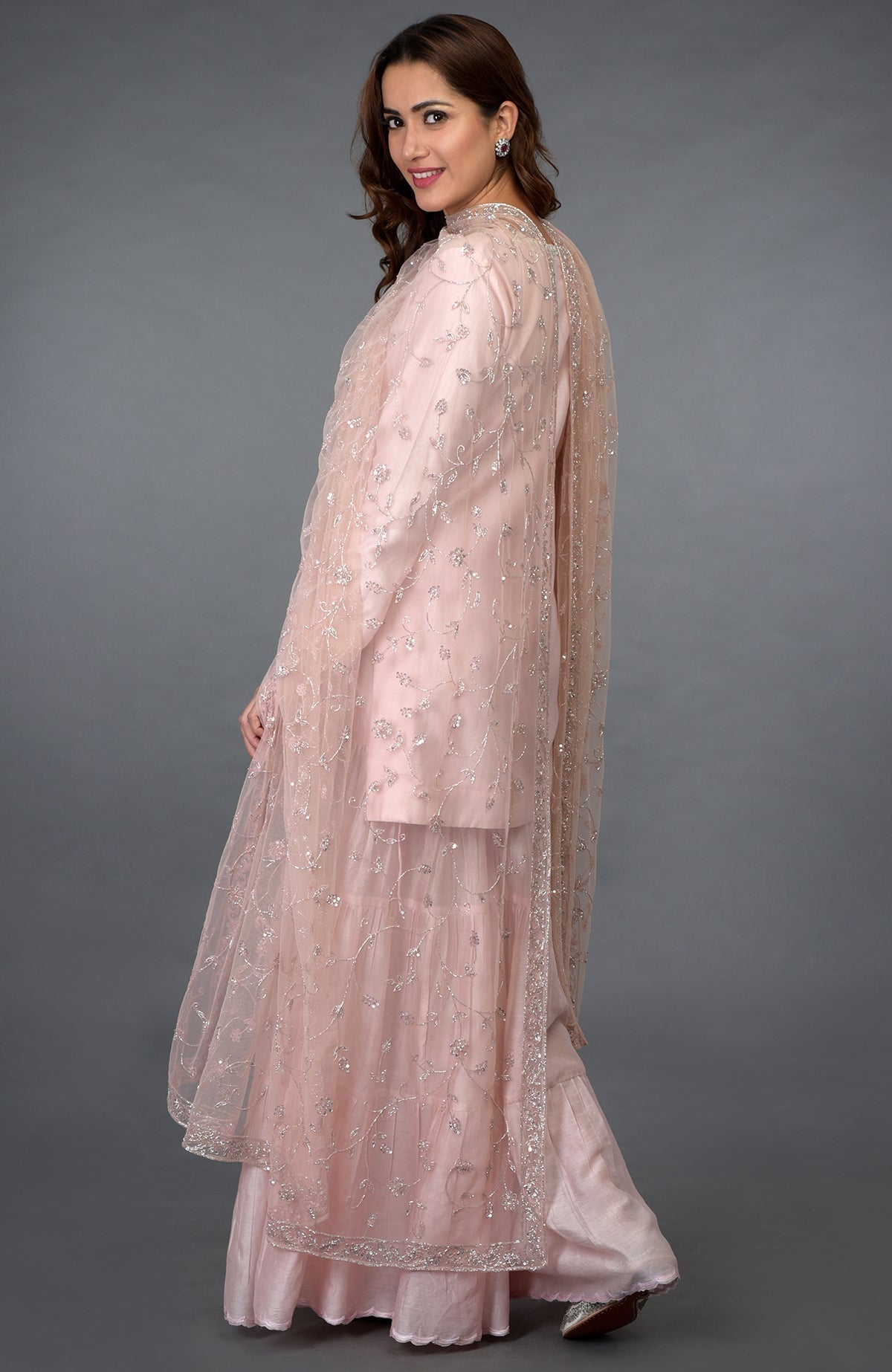 Pink-silver zari, beads, and sequin embroidered gharara suit with a net dupatta.