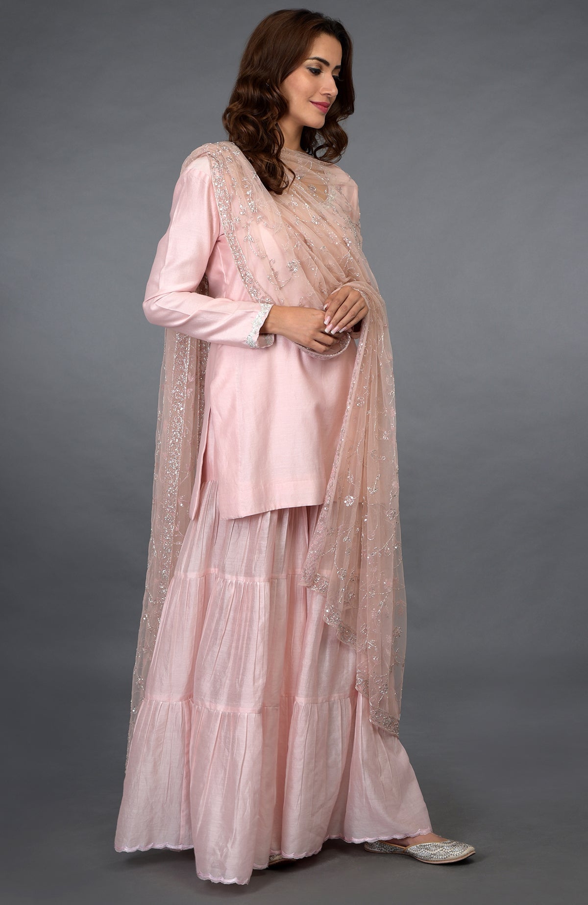 A woman models a pink-silver zari beads and sequin embroidered gharara suit.