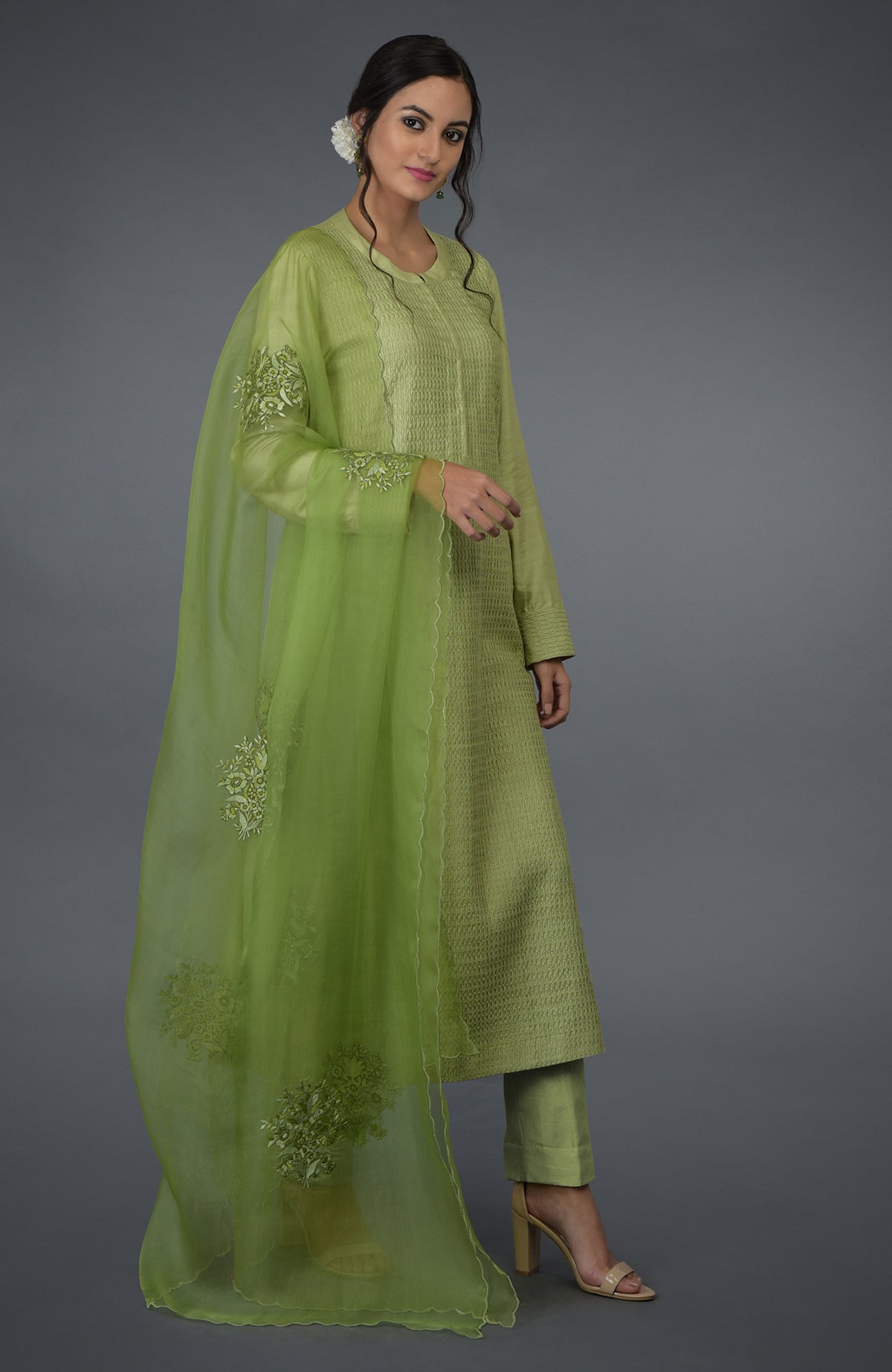 A woman models a pista green pintuck silk kurta set with an embroidered dupatta.