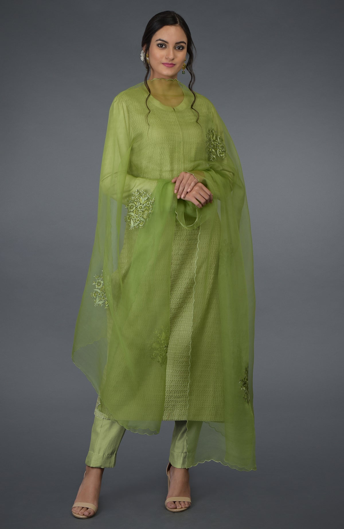 A woman models a pista green pintuck silk kurta set with a matching dupatta.