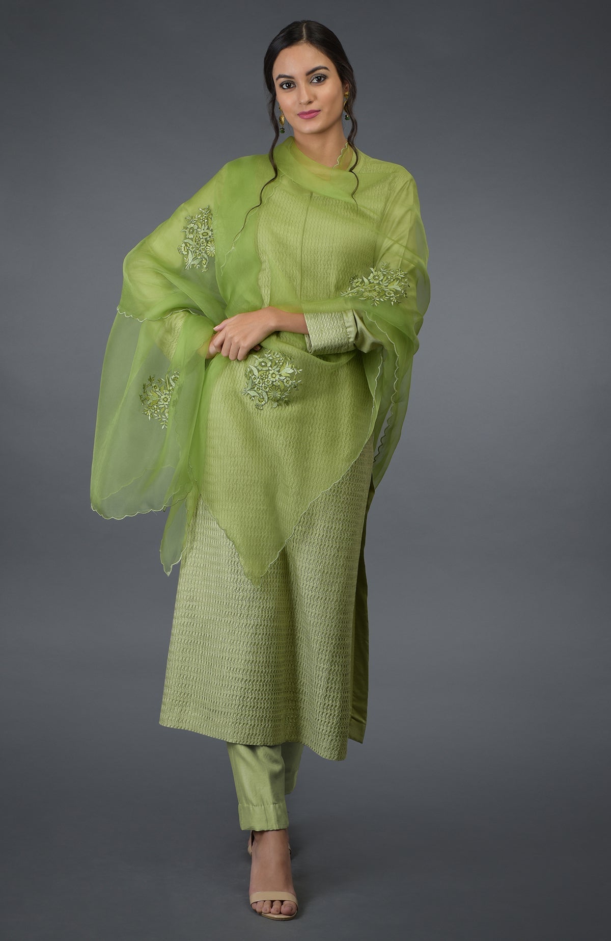 A woman models a pista green pintuck silk kurta set with an embroidered dupatta.