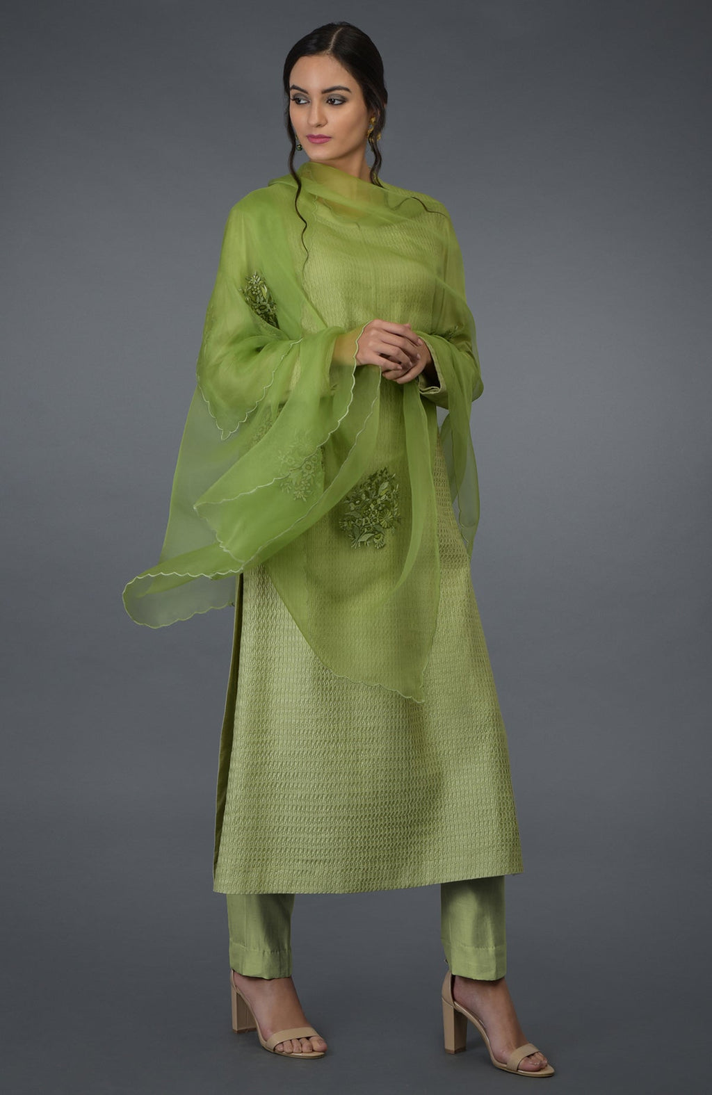 A woman models a pista green pintuck silk kurta set with an embroidered dupatta.