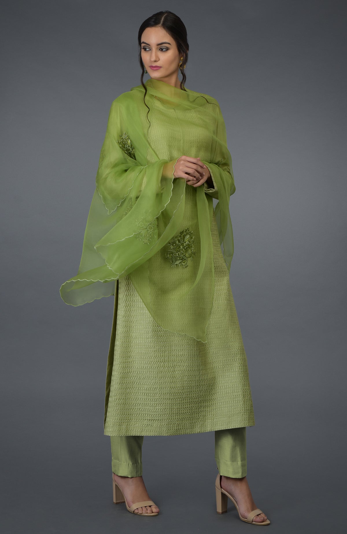 A woman models a pista green pintuck silk kurta set with an embroidered dupatta.
