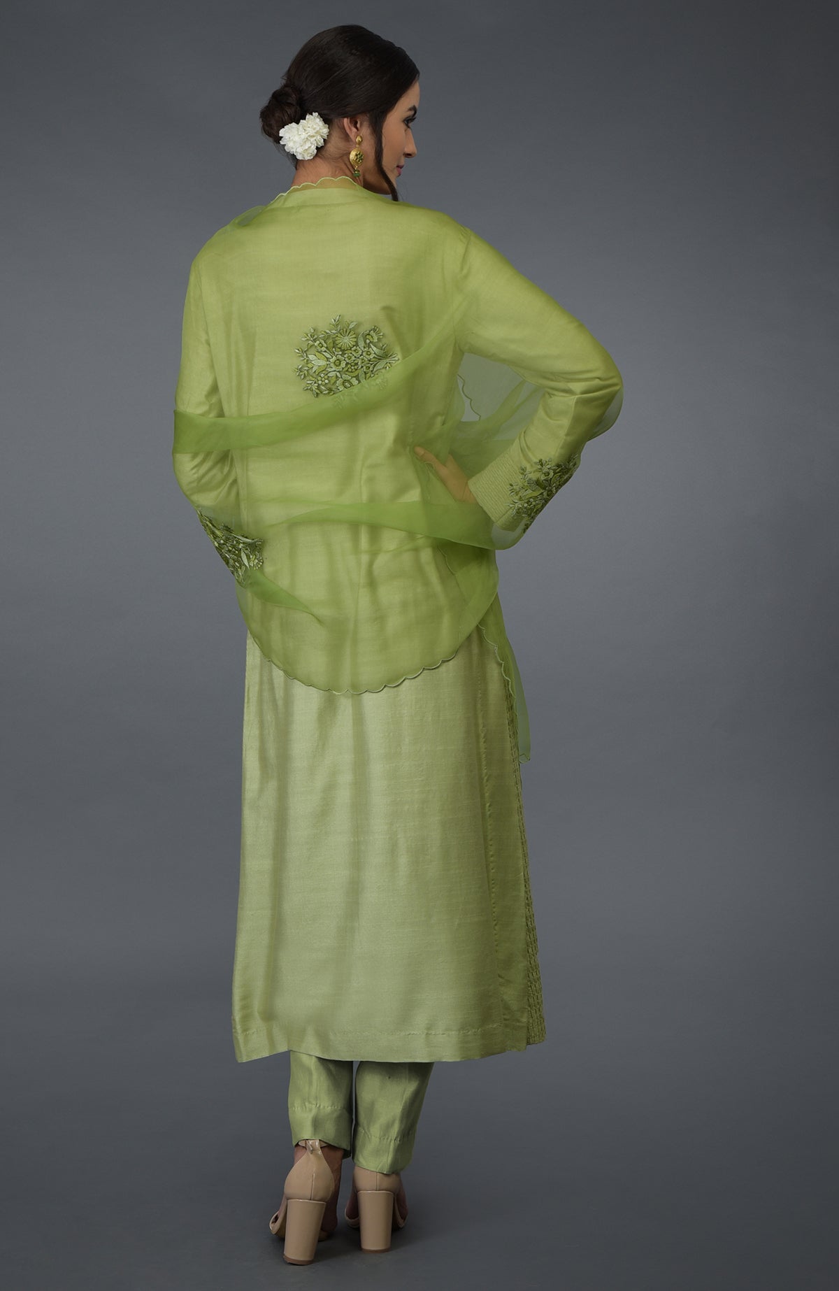 A woman models a pista green pintuck silk kurta set with an embroidered dupatta.