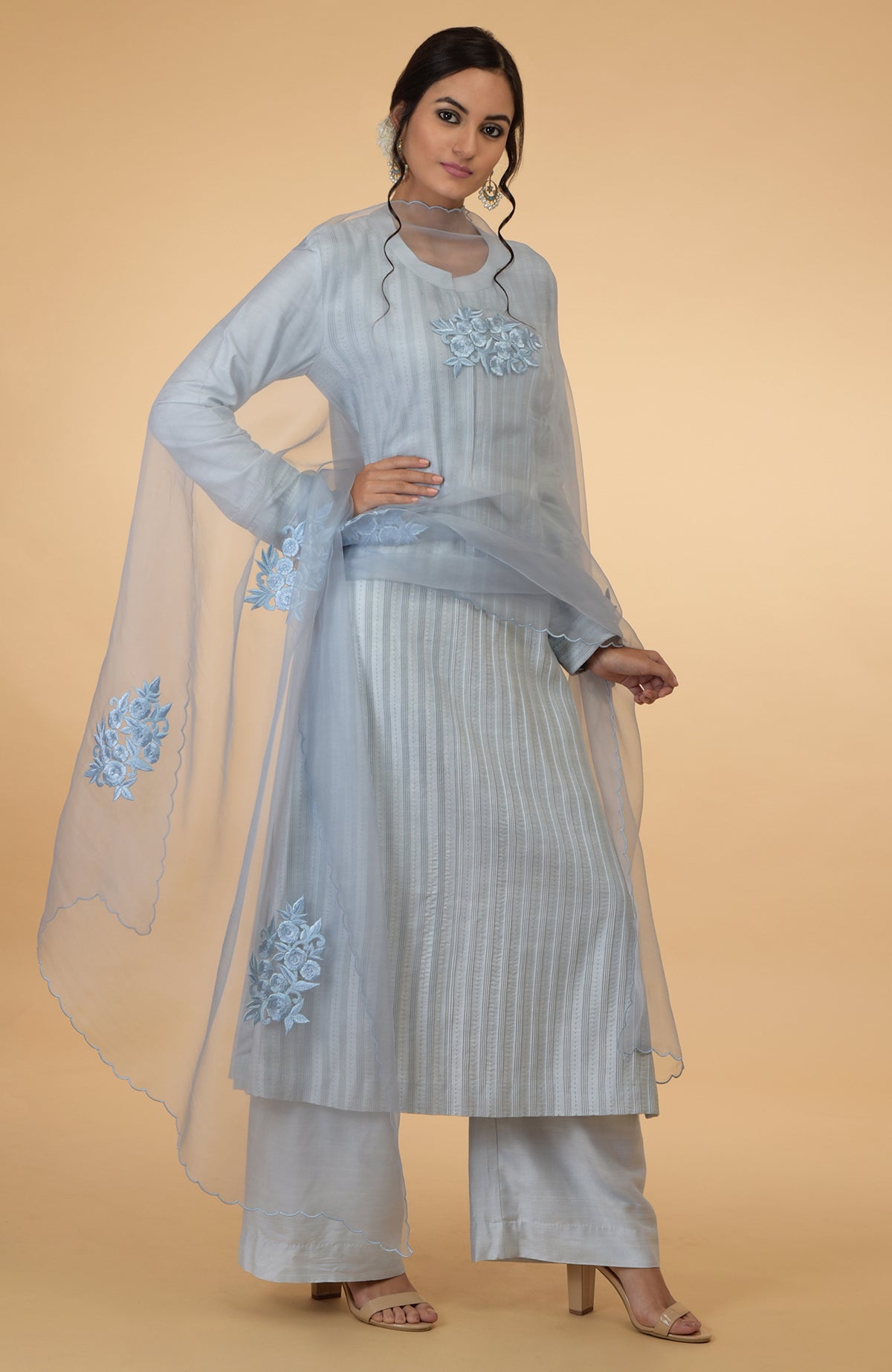 A woman models a powder blue pintuck and Kantha silk kurta set with a dupatta.