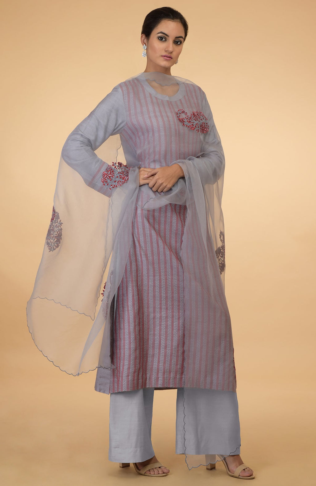 A woman models a grey and maroon Kantha embroidered kurta set with a dupatta.