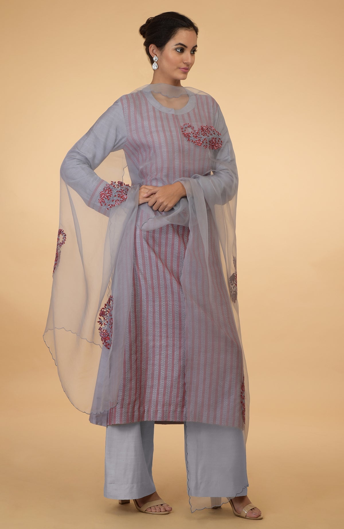 A woman models a grey and maroon Kantha embroidered kurta set with a dupatta.