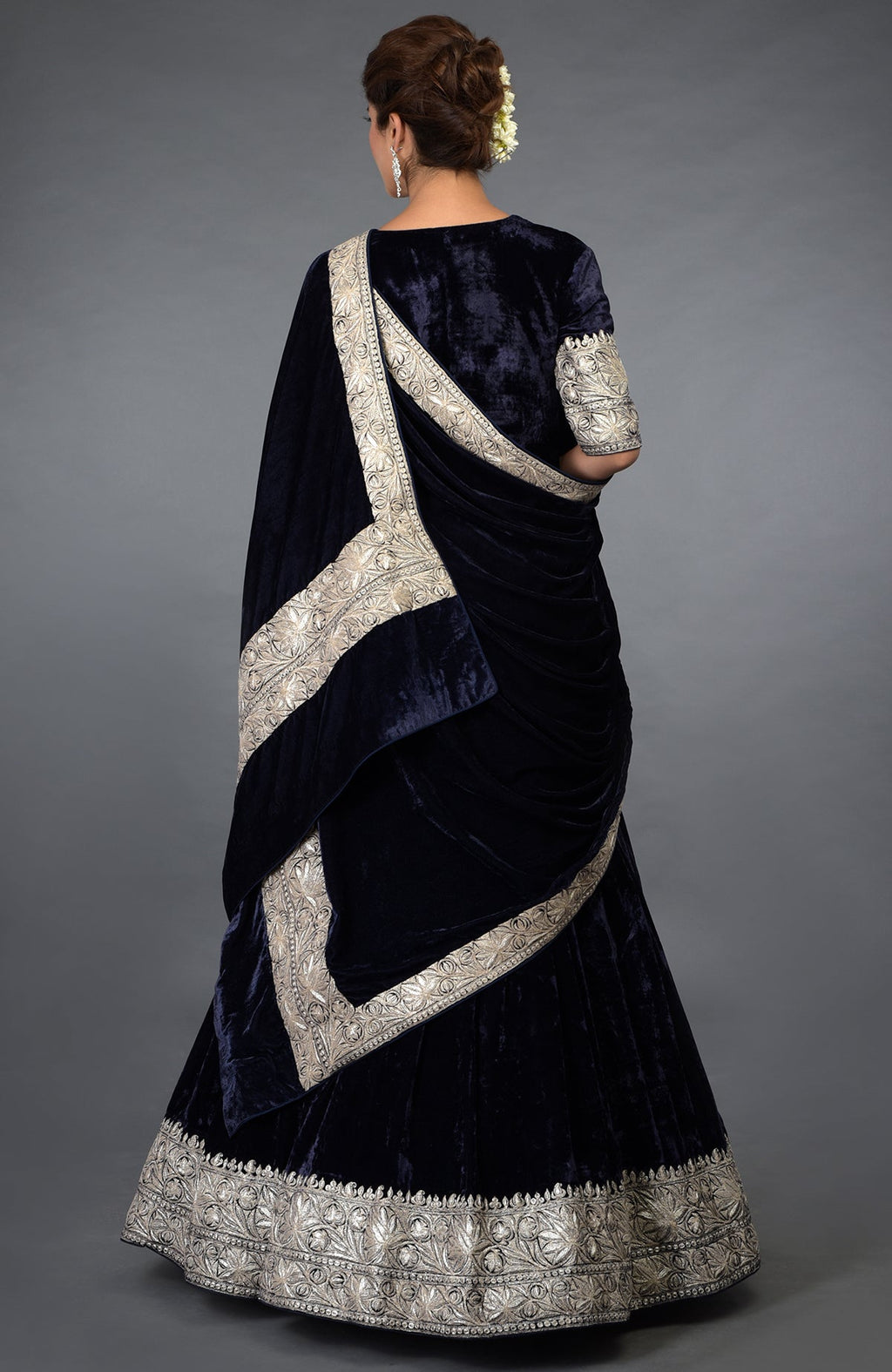 A woman models a midnight blue velvet lehenga with silver tilla embroidery.