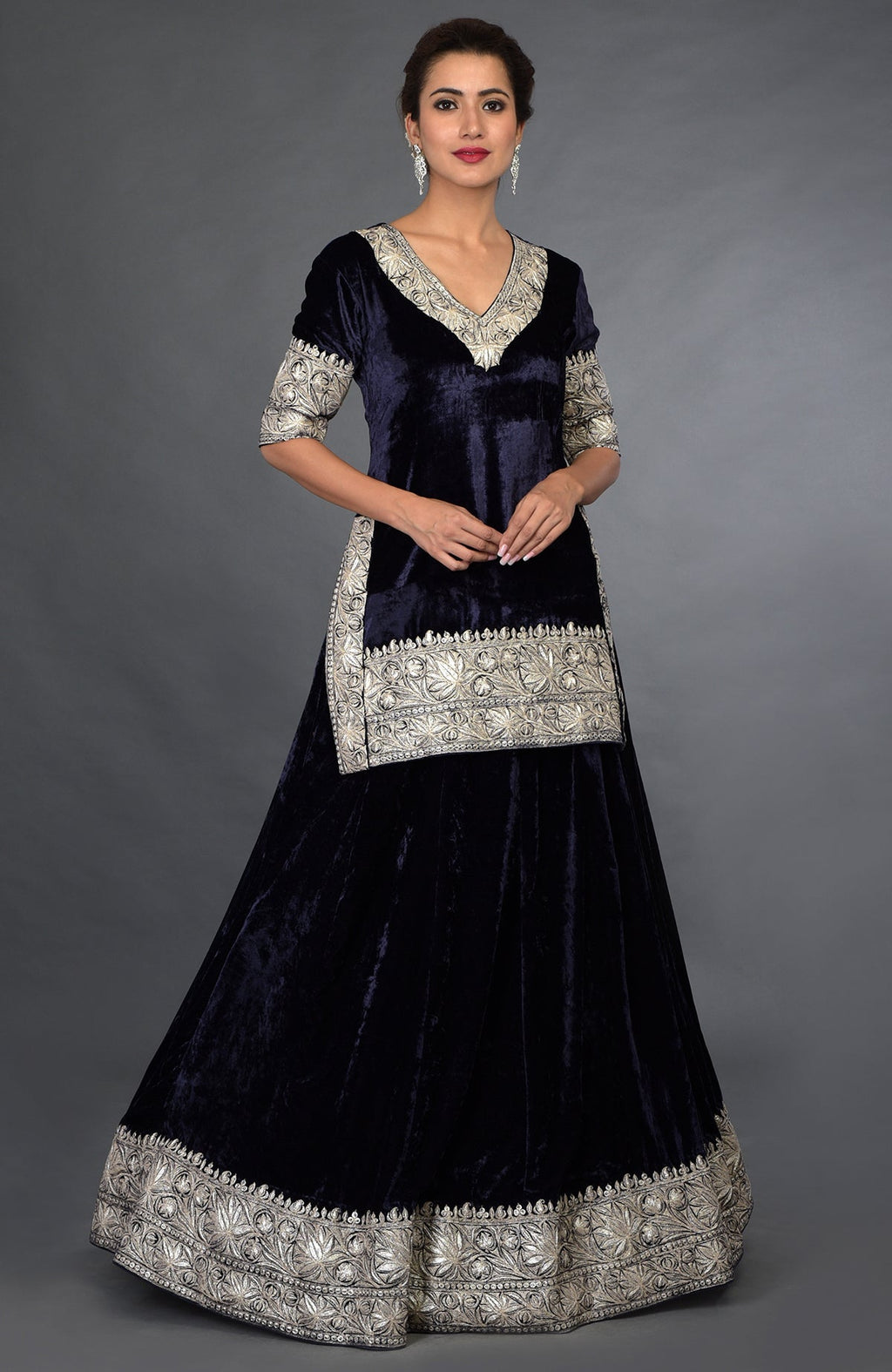 A woman models a midnight blue velvet lehenga with silver Kashmiri Tilla embroidery.