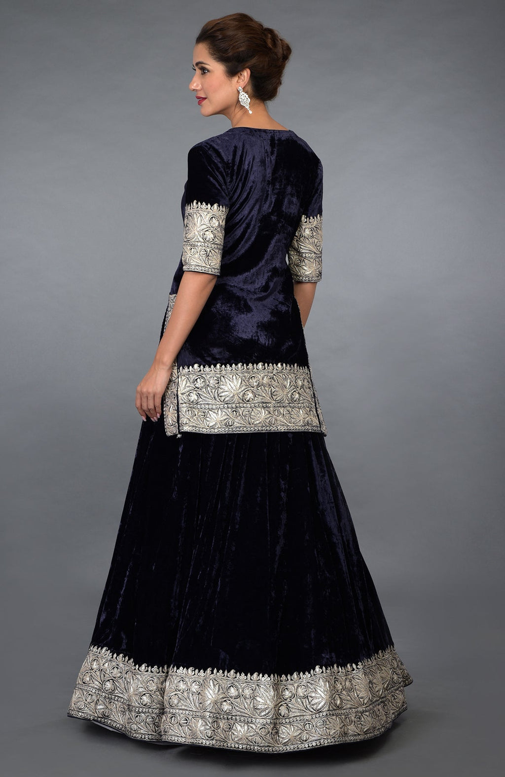 A woman models a midnight blue velvet lehenga with silver Kashmiri Tilla embroidery.