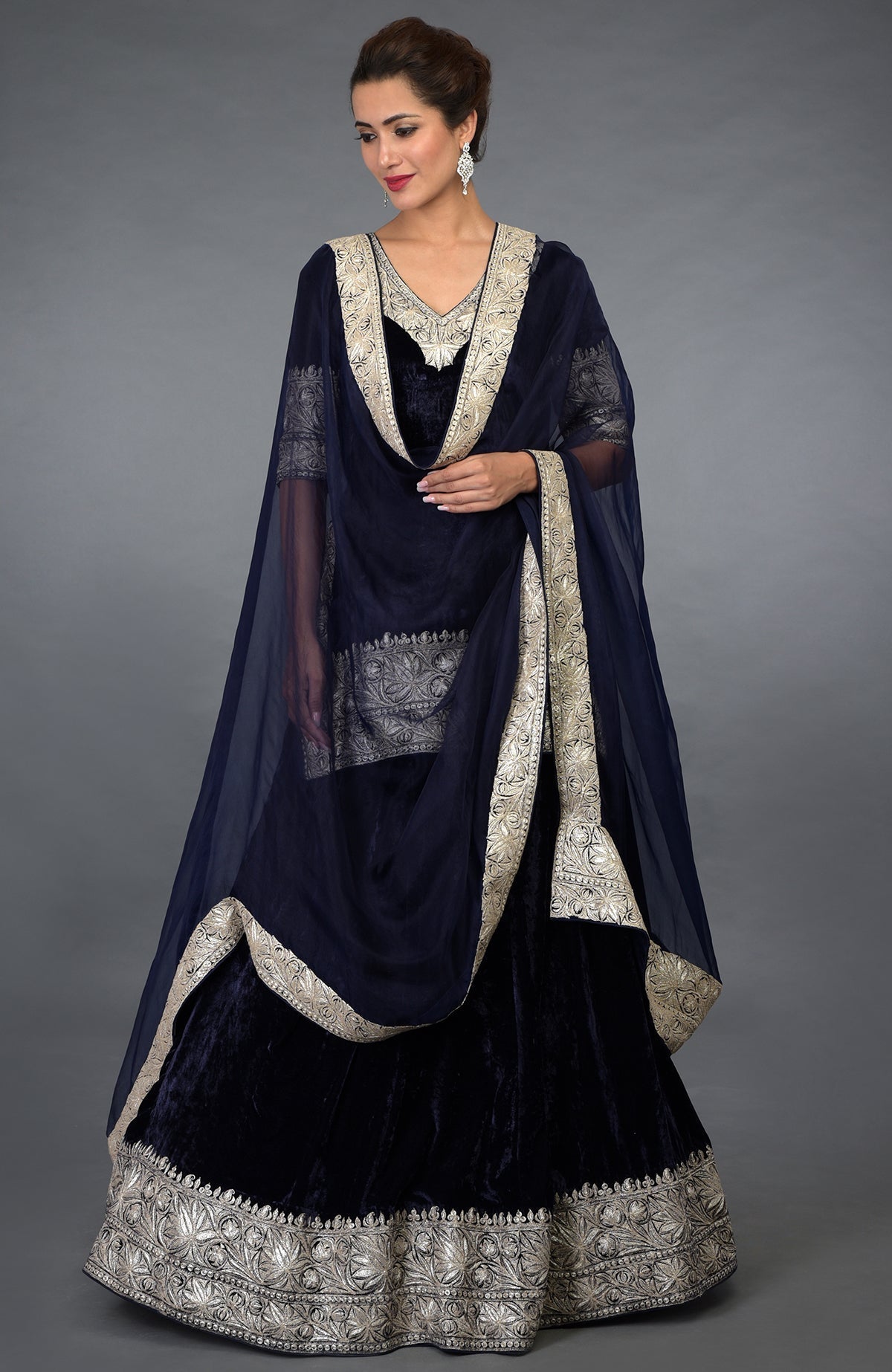 A woman models a midnight blue velvet lehenga with silver tilla embroidery.