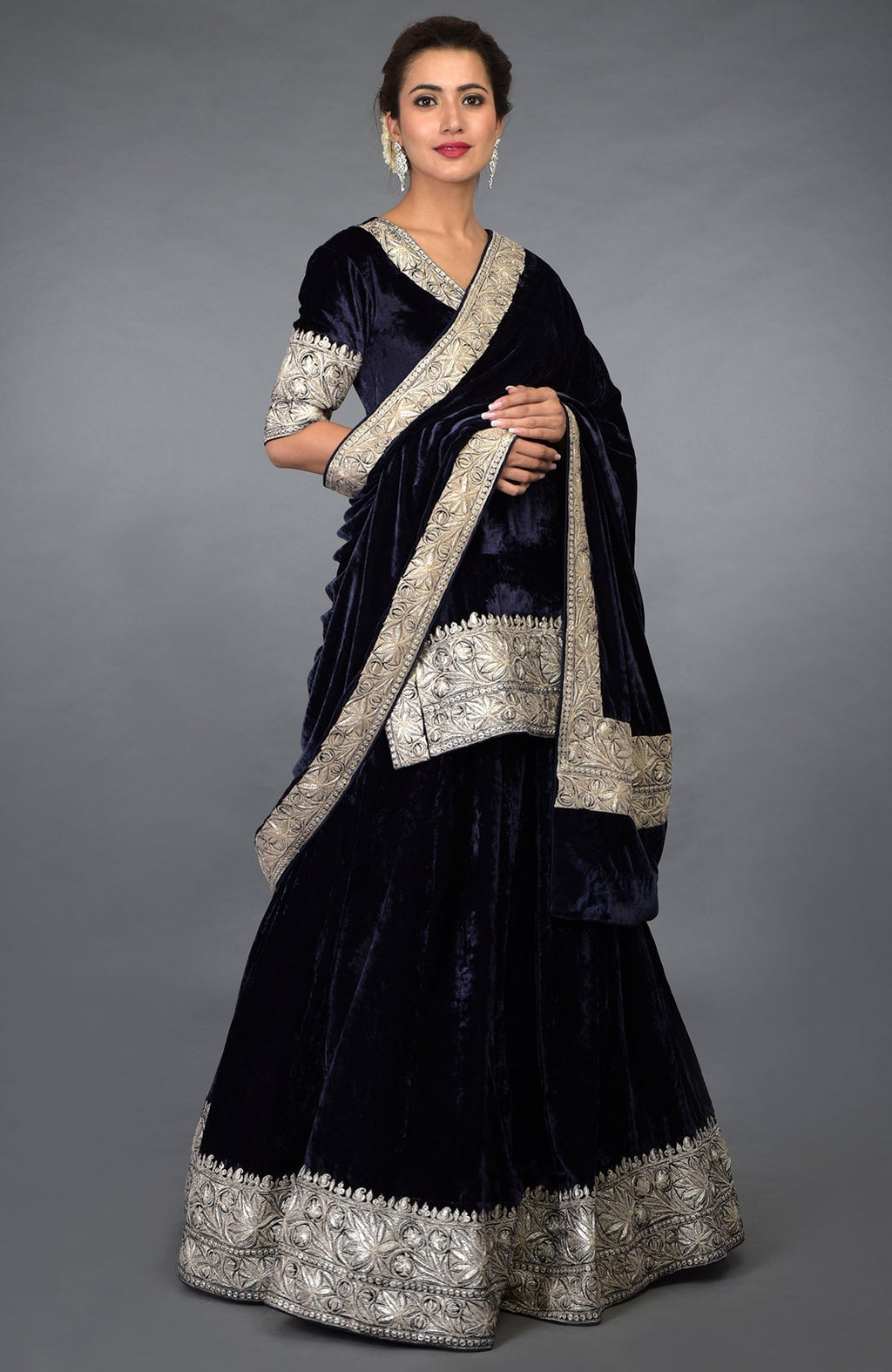 A woman models a midnight blue velvet lehenga with silver Kashmiri Tilla embroidery.