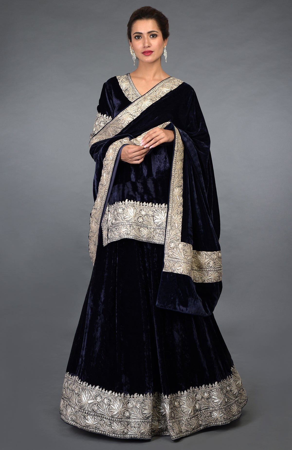 A woman models a midnight blue velvet lehenga with silver tilla embroidery.