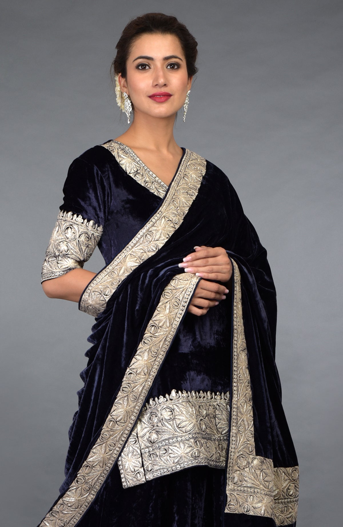 A woman models a midnight blue velvet lehenga with intricate silver tilla embroidery.