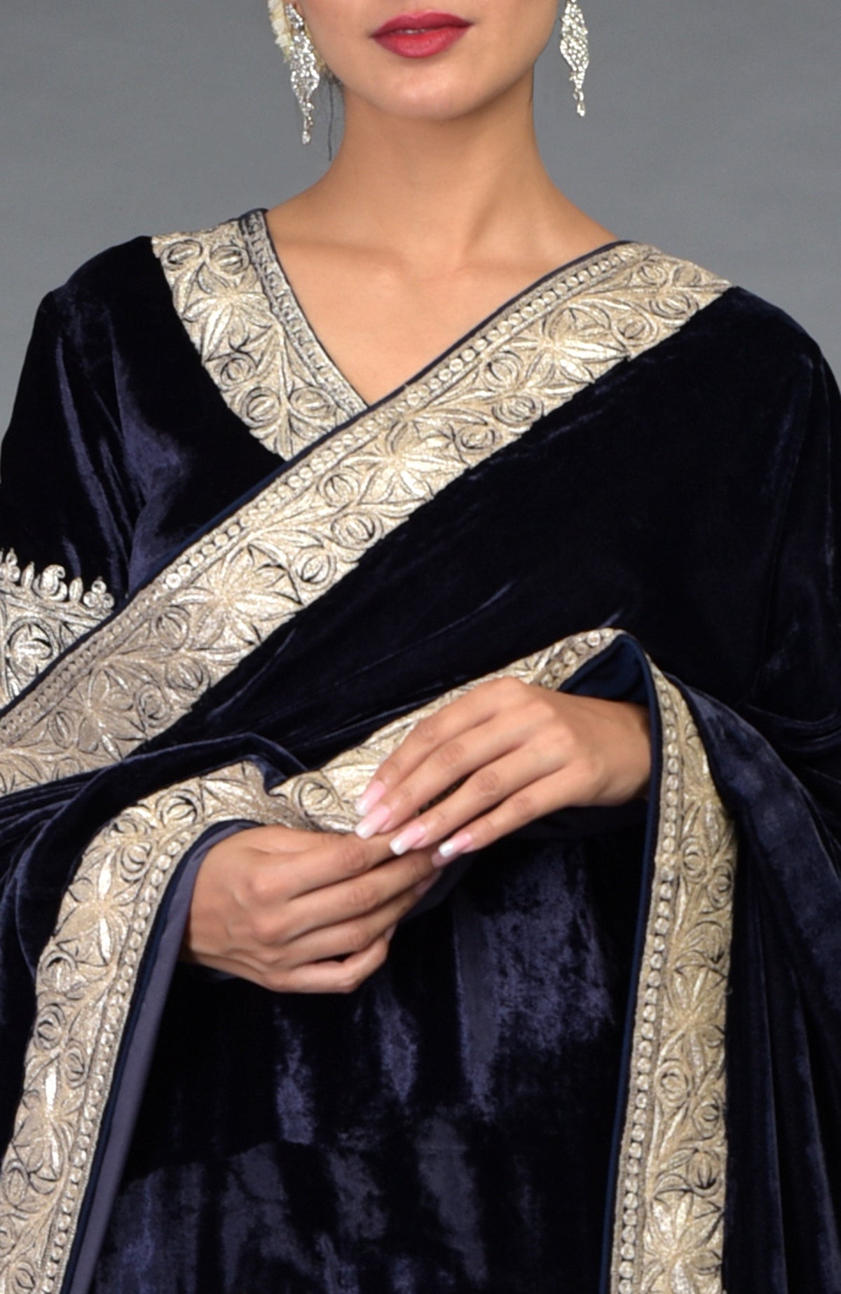 A woman models a midnight blue velvet lehenga with silver tilla embroidery.