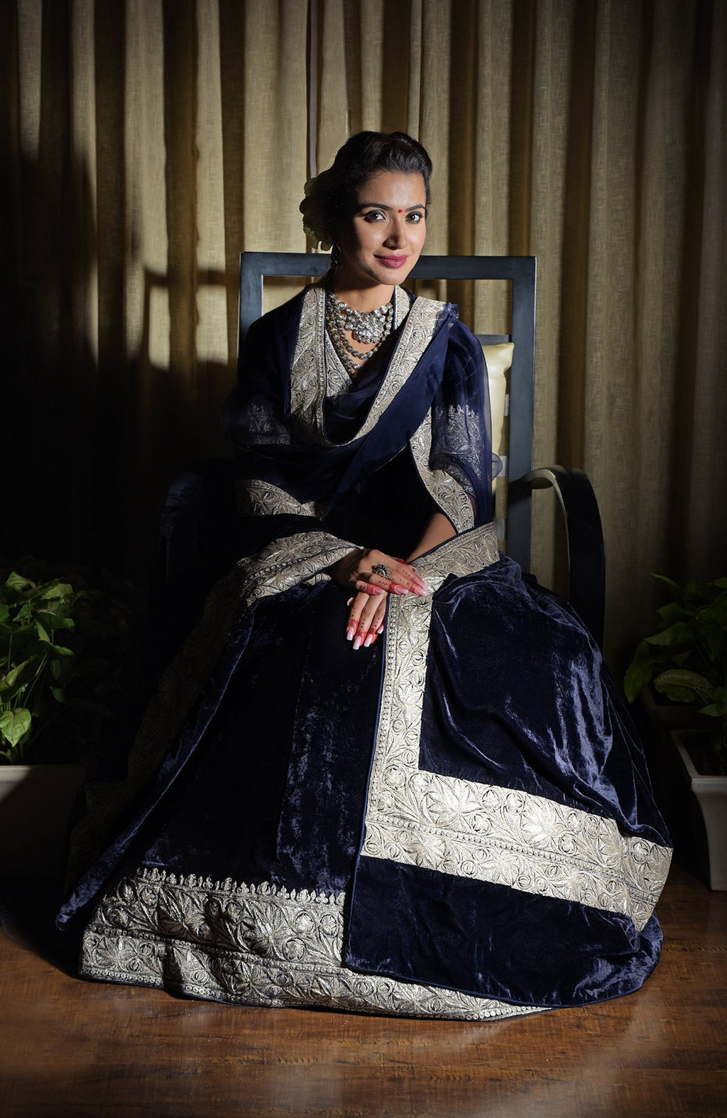 A woman models a midnight blue velvet lehenga with silver tilla embroidery.