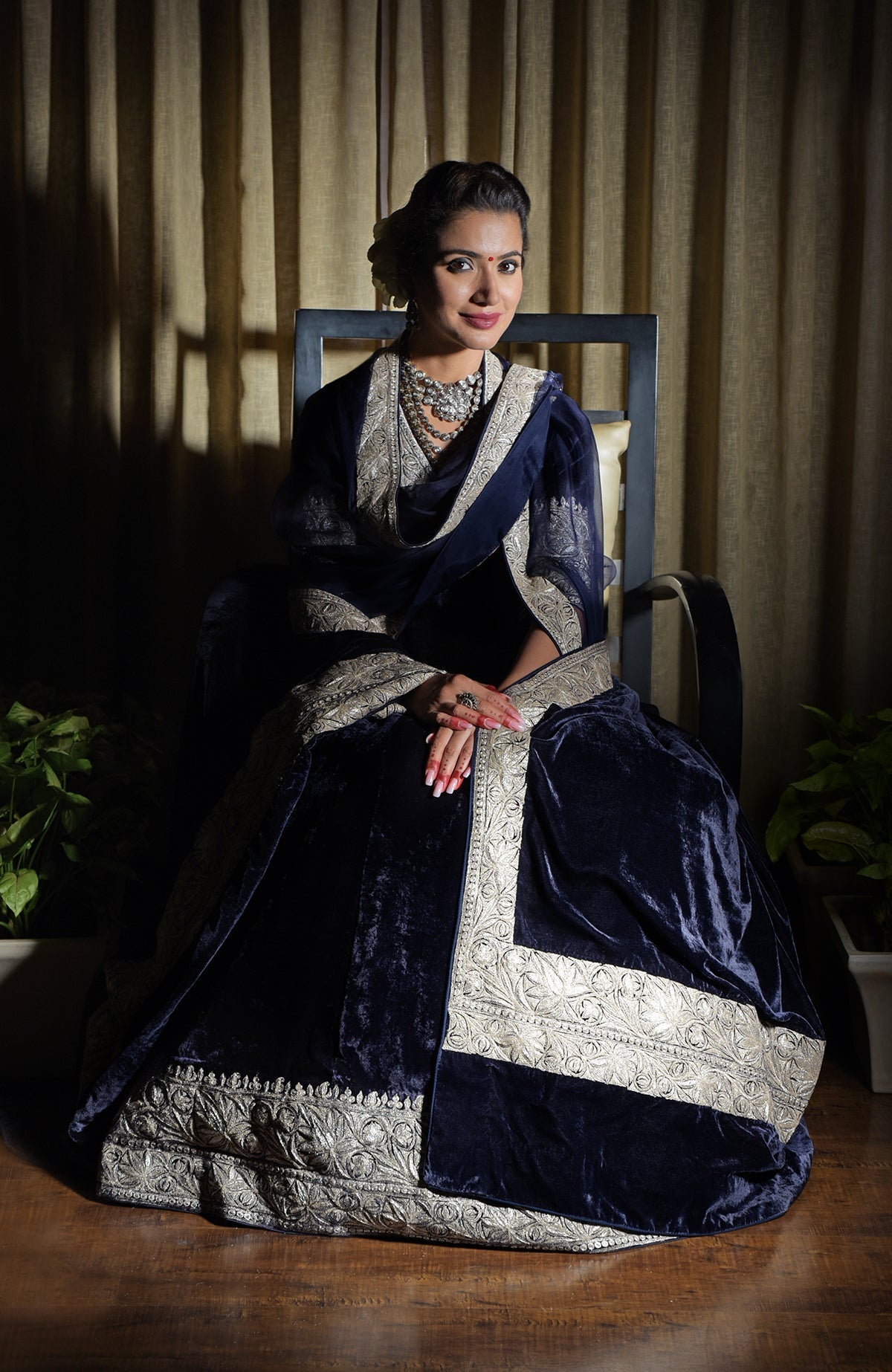 A woman models a midnight blue velvet lehenga with silver tilla embroidery.