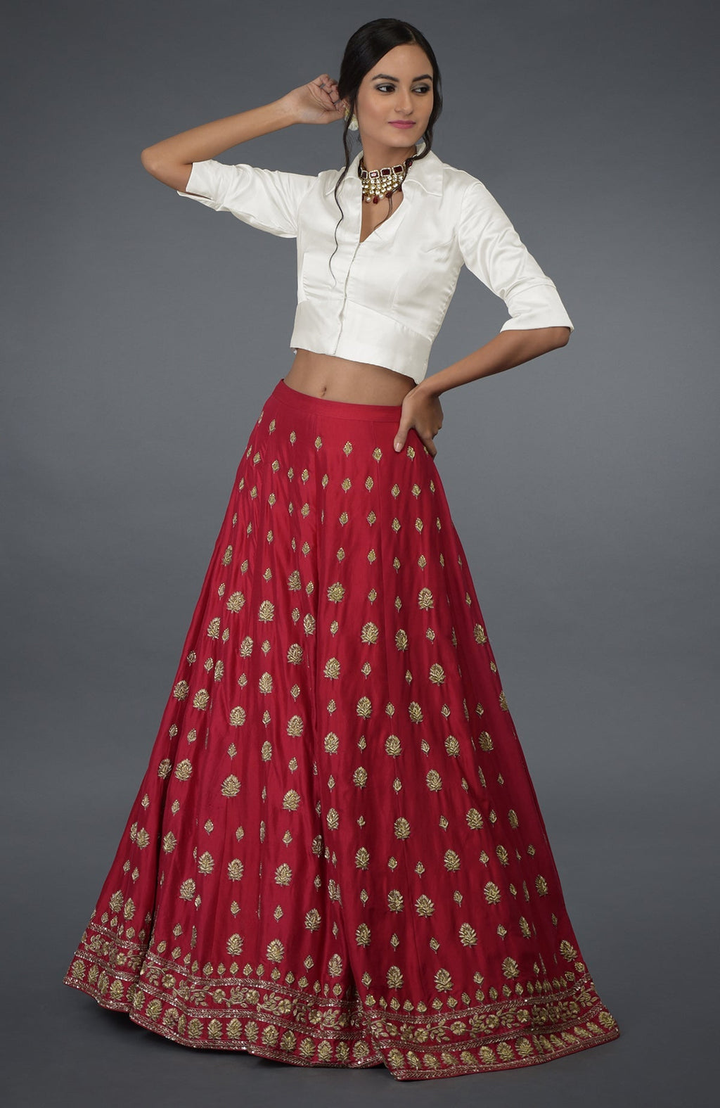 A woman models a red embroidered skirt and a white collared crop top.