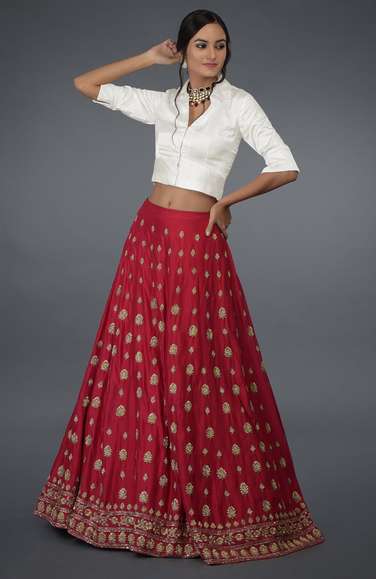 A woman models a red embroidered skirt and a white collared crop top.