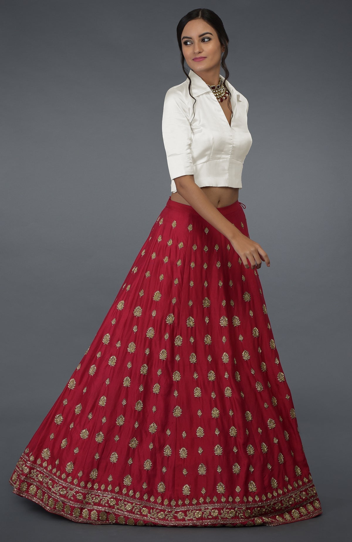 A woman models a red embroidered skirt and an ivory satin blouse.
