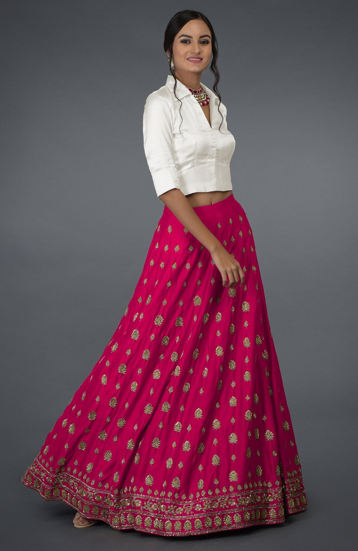 A woman models a berry gloss zardozi and crystal hand-embroidered skirt with a blouse.